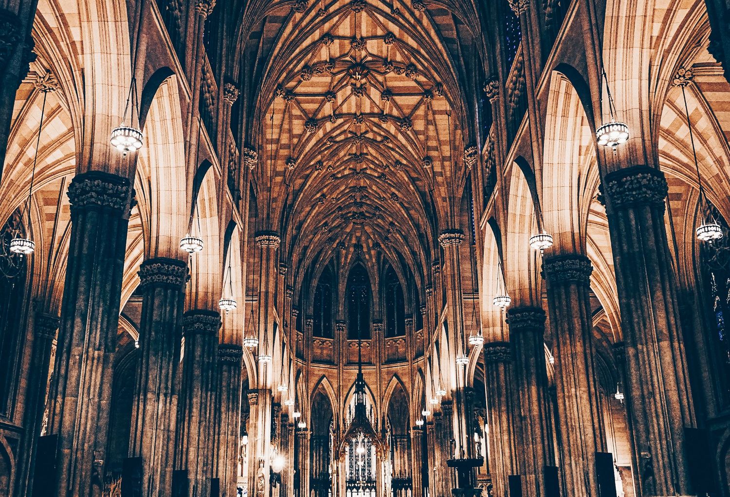 Gothic cathedral interior with vaulted ceilings and ornate architectural details in sepia tones.