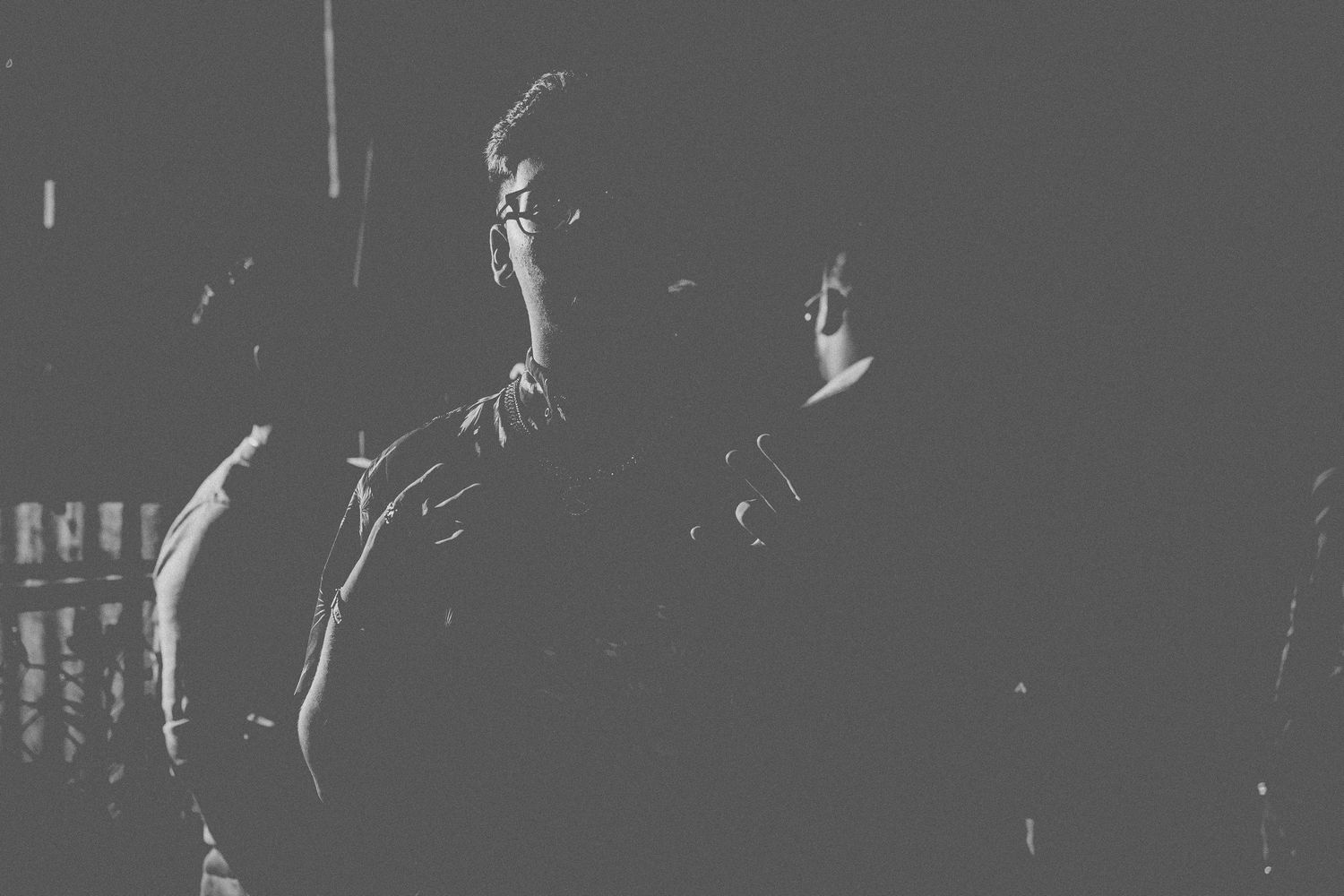 High contrast black and white photo of people standing in shadows.