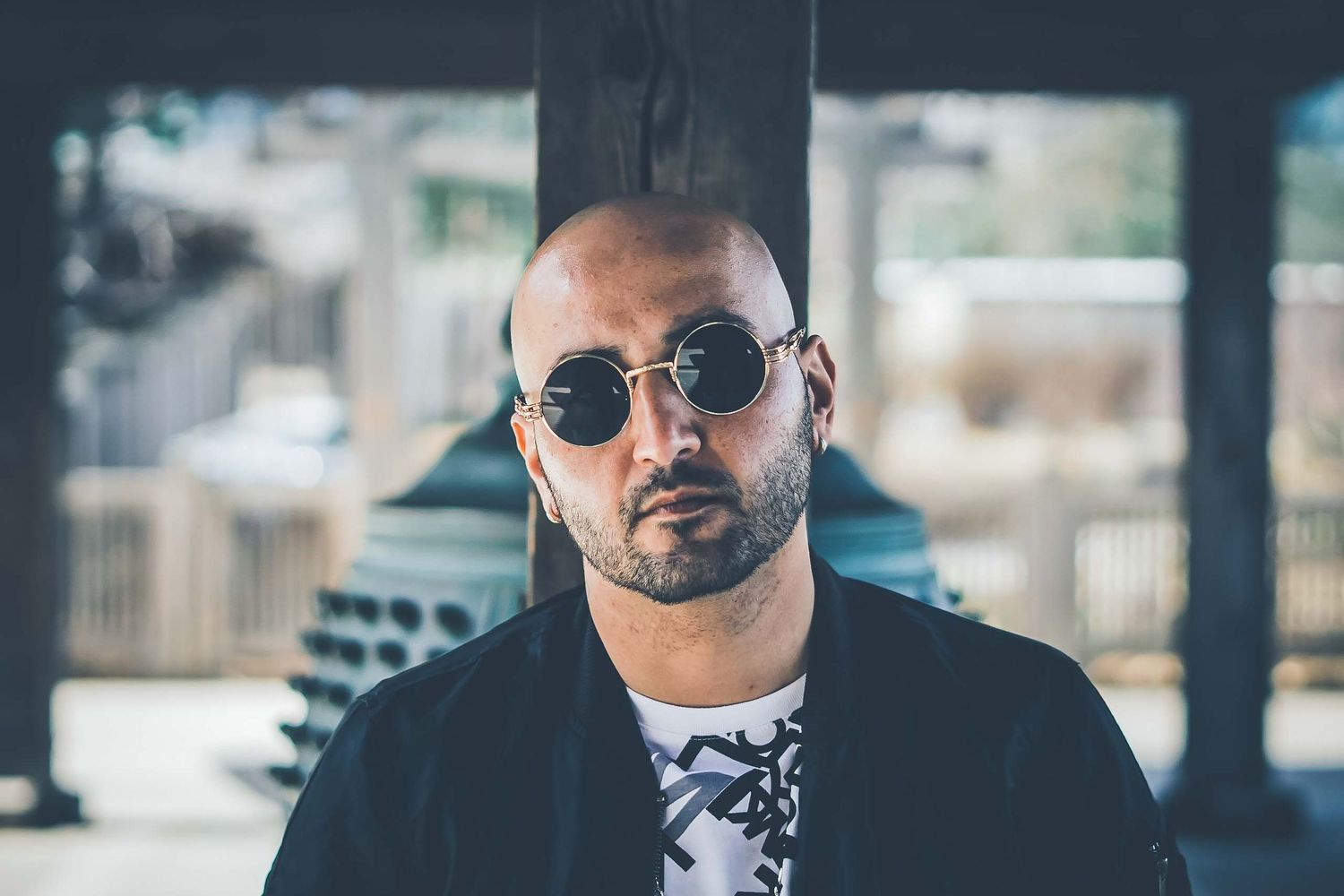 Urban portrait of person wearing sunglasses and black jacket.
