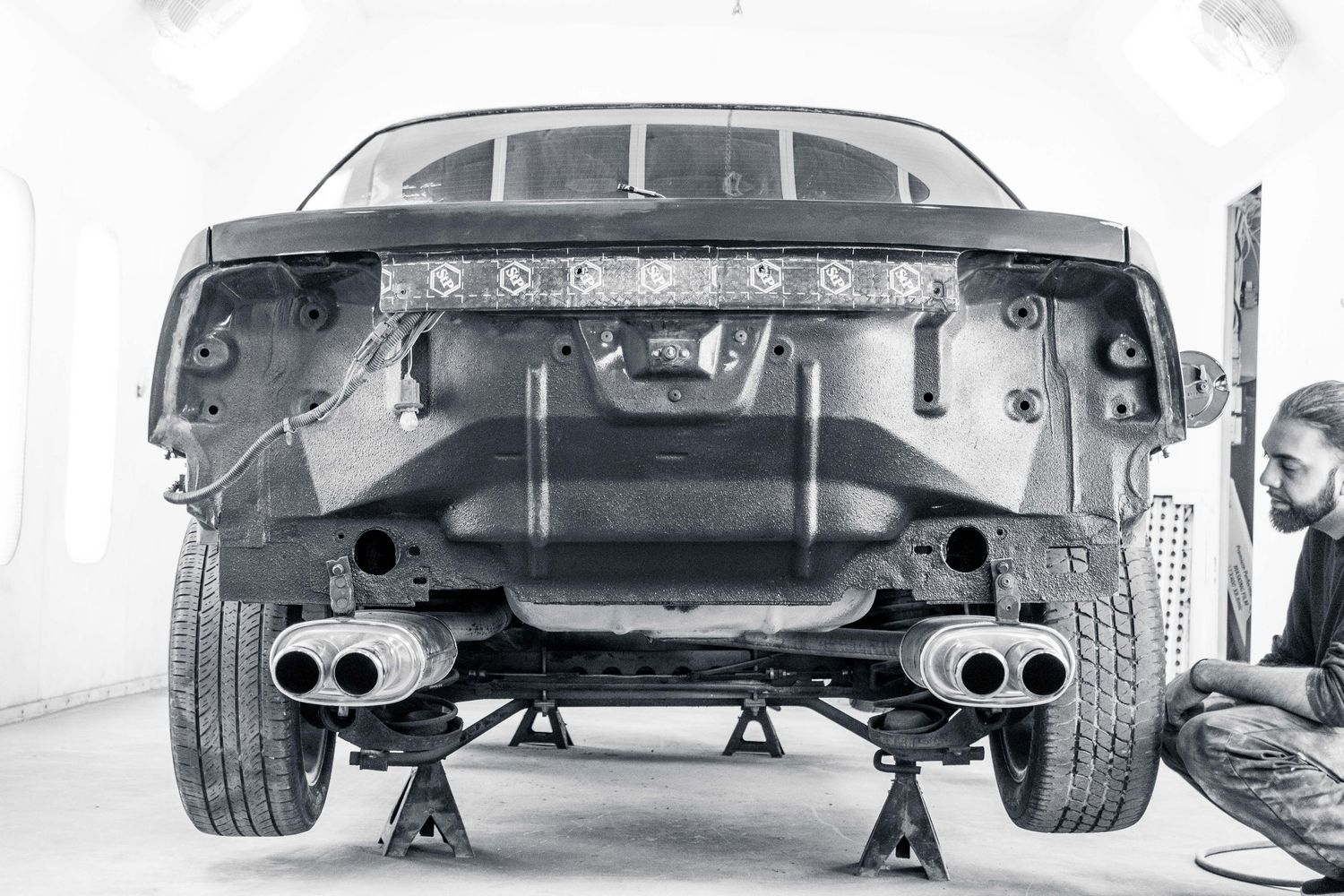 Close-up view of a classic car's undercarriage showing dual exhaust pipes and suspension components.