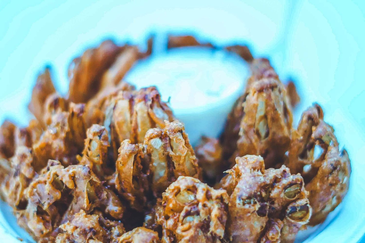 Close-up of crispy fried onion strings on a blue background.