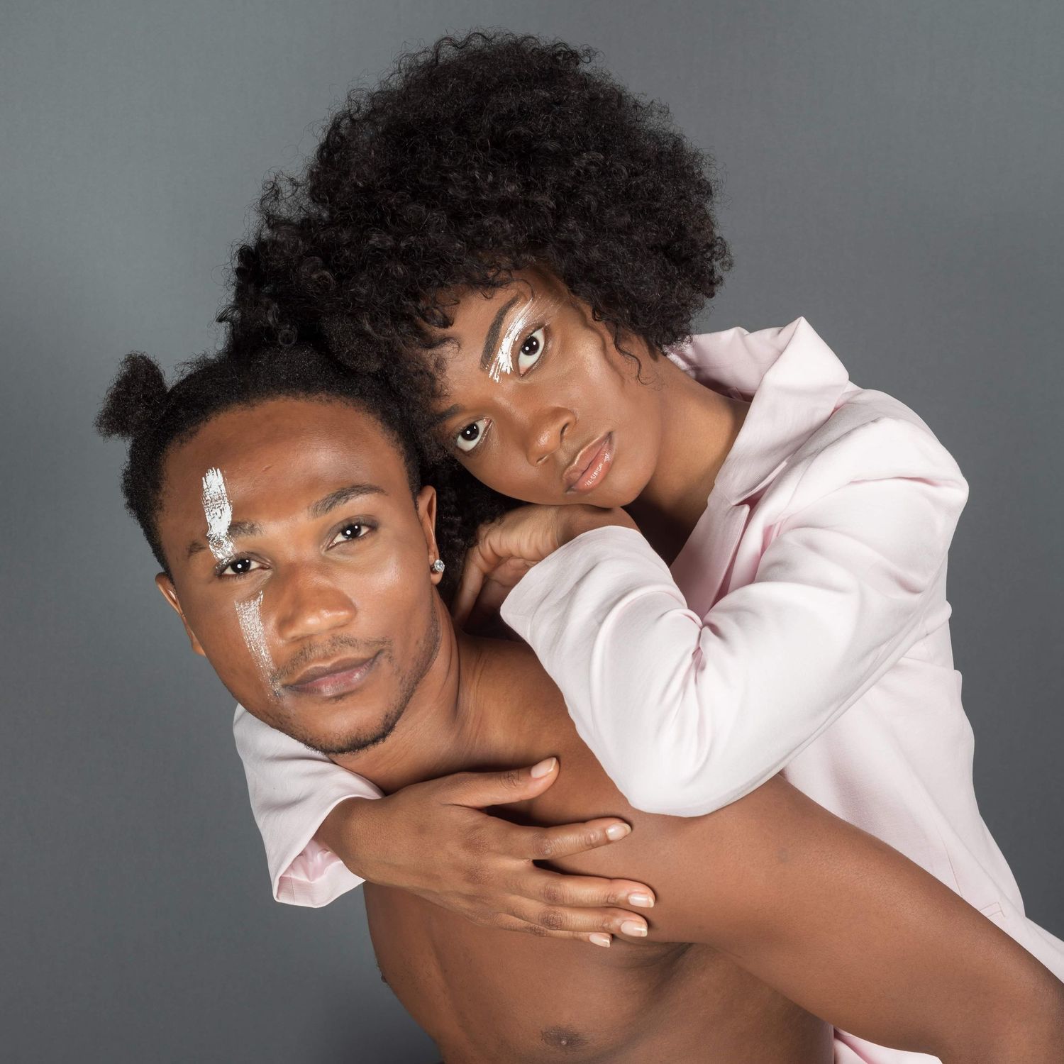 un jeune couple pose ensemble sur fond gris.