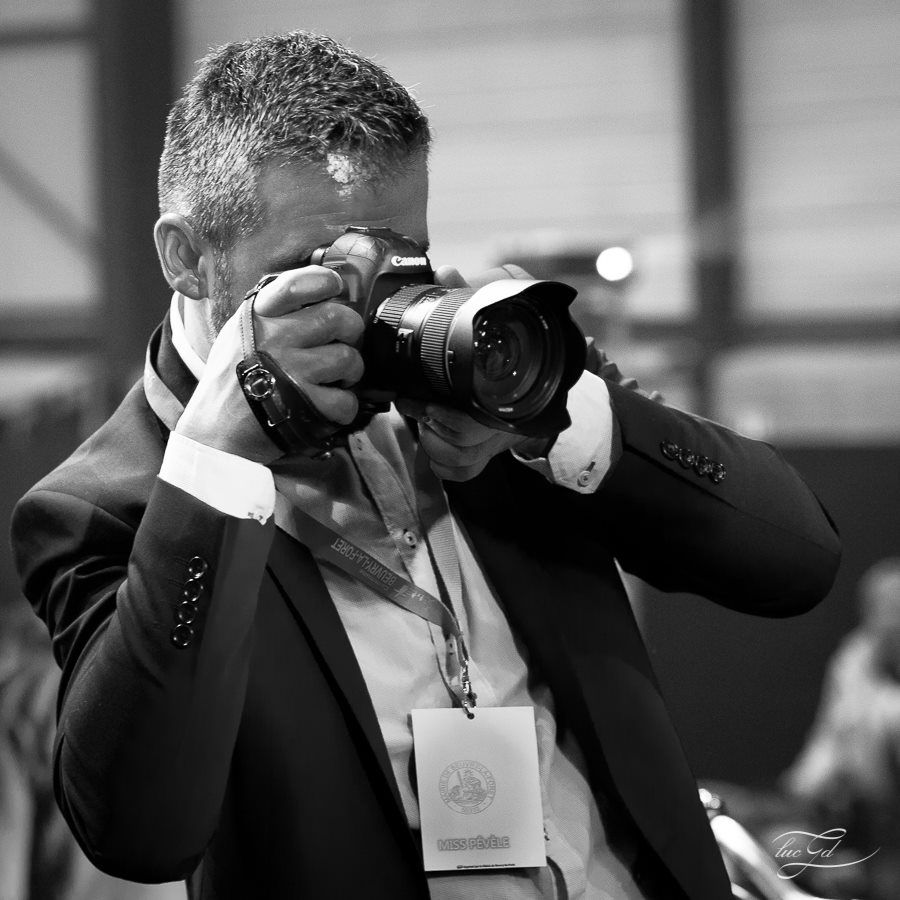 Michael GHYS, Professional photographer in suit captures images with Canon camera at formal event in black and white.