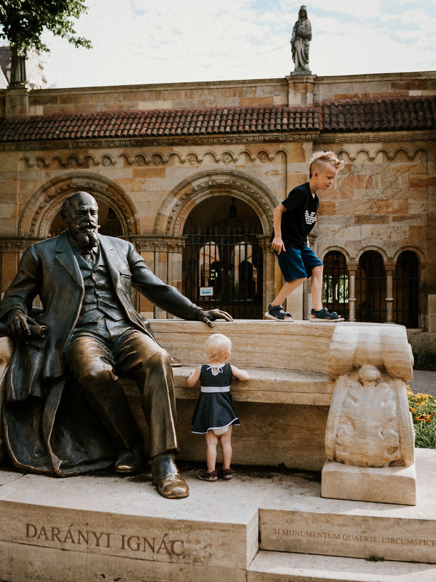 Siblings playing together near a statue at Vajdahunyad Castle