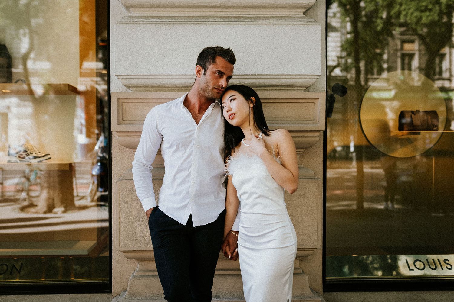 International couple leaning at the wall of a building, posing for their portrait