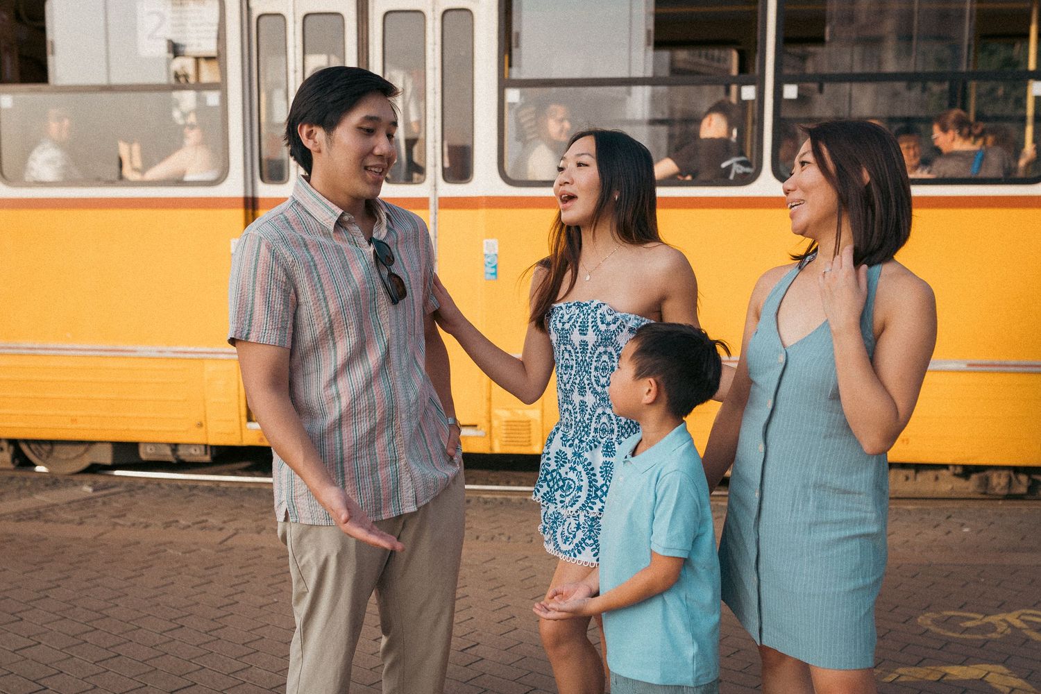 Mom and her three kids talking and having fun during their Budapest photo shoot, while a tram goes through in the background