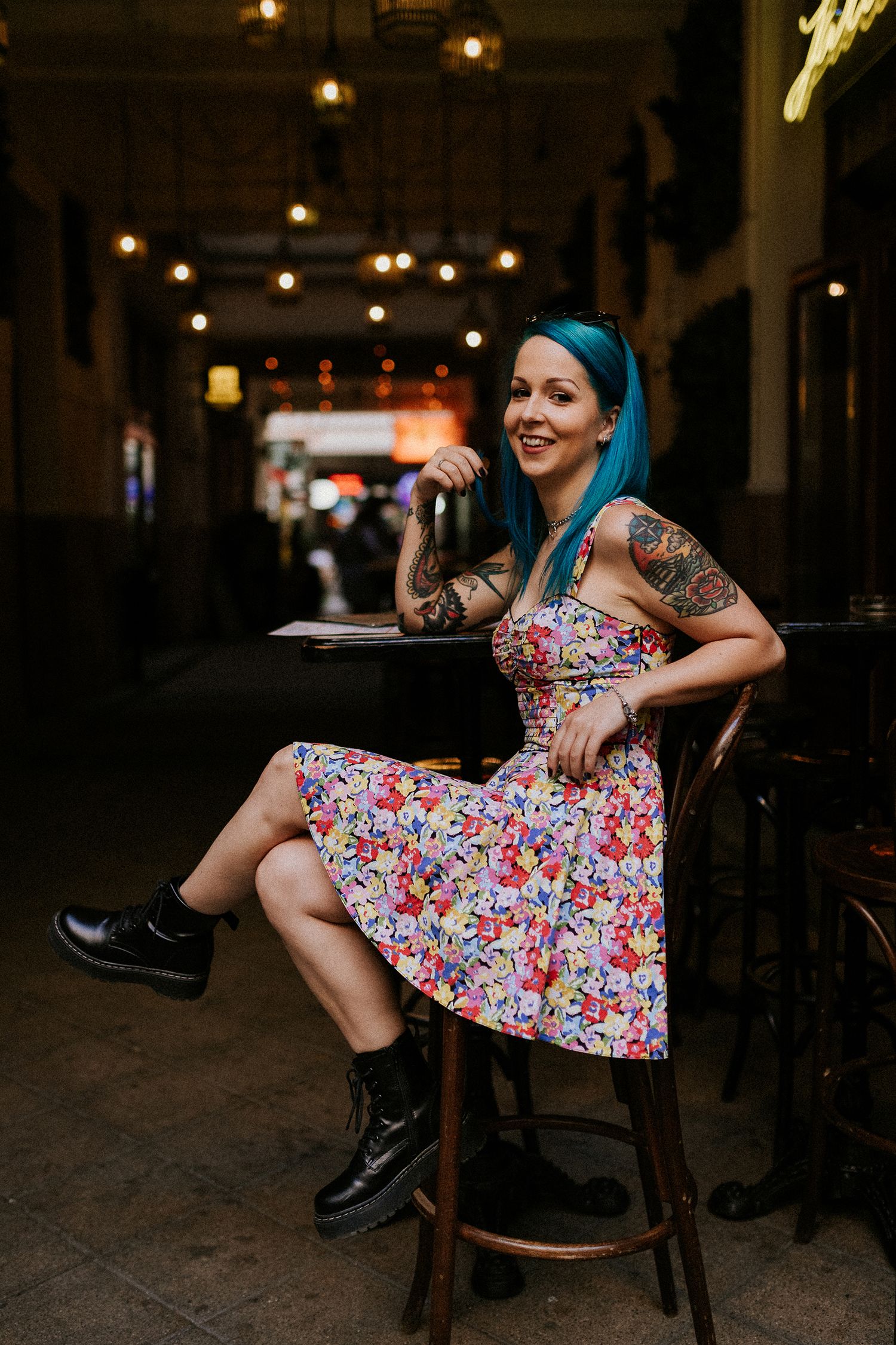 Young woman sitting on a chair in front of a bar at Gozsdu Udvar in Budapest, posing for her portraits