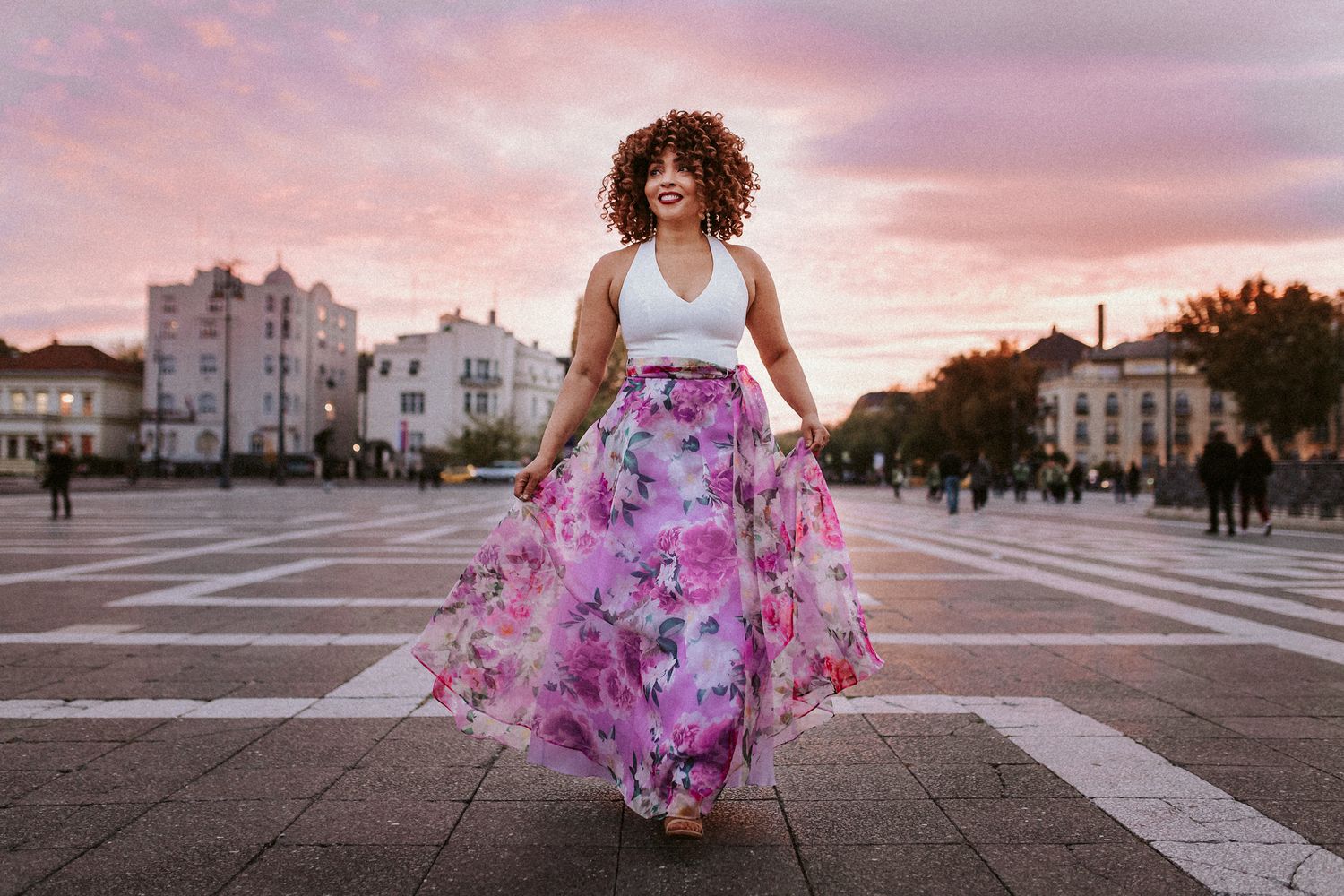 Woman walking at Heroes' square in Budapest in the sunset. Both her dress and the sky is purple and pink