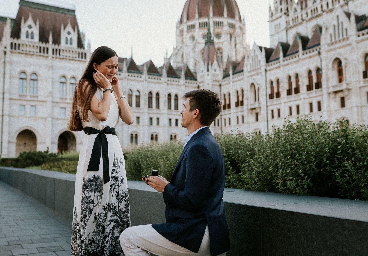 Young woman in tears when her boyfriend kneels down to propose her in front of the Hungarian Parliament building