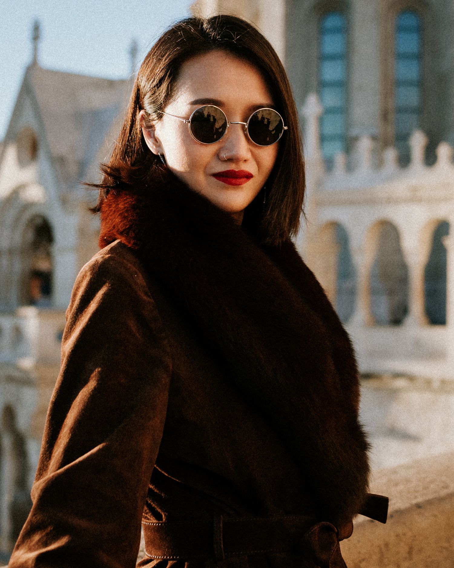Young woman in winter coat and sunglasses, looking in the camera for her portrait