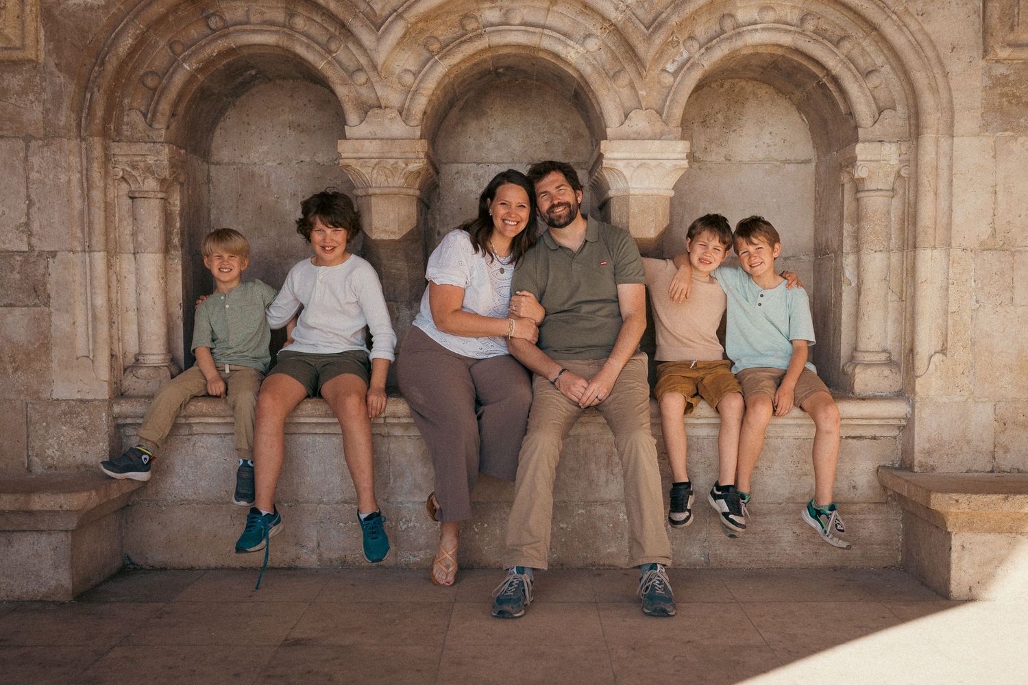 Mom, dad, and their four children sitting in the shadow, and looking in the camera of the local photographer