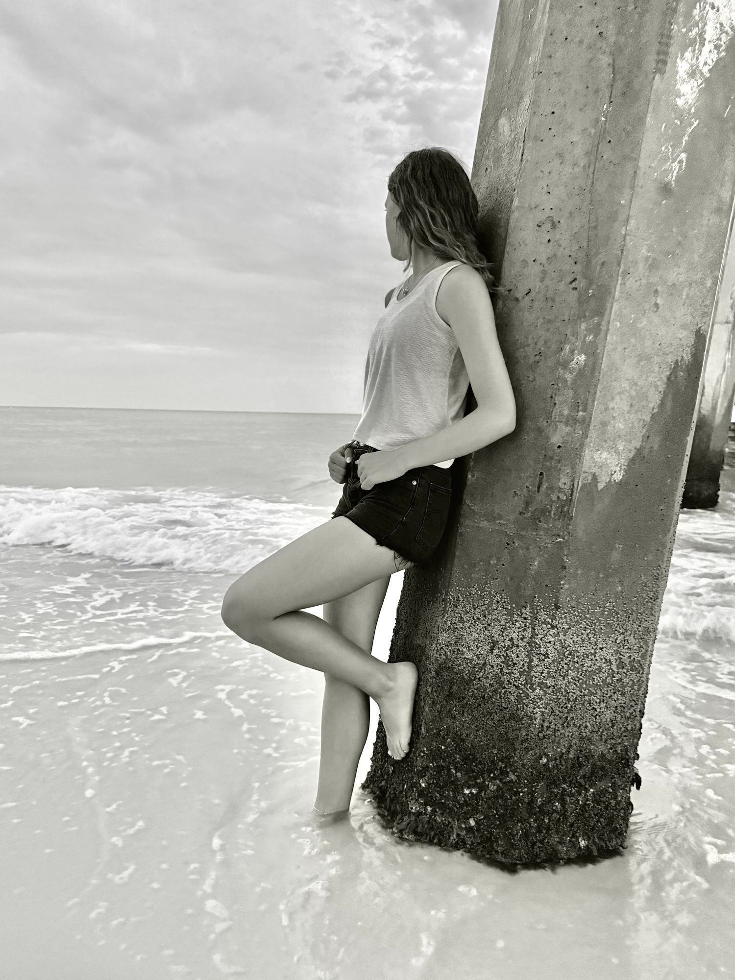 Young girl leaning against a pier in the ocean