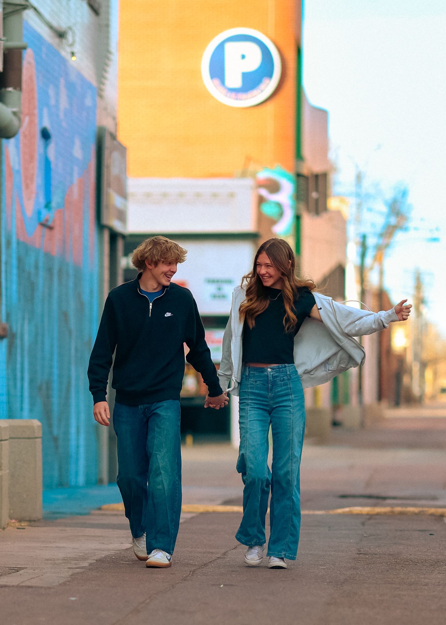 Young couple walking down a city alley holding hands and looking at each other