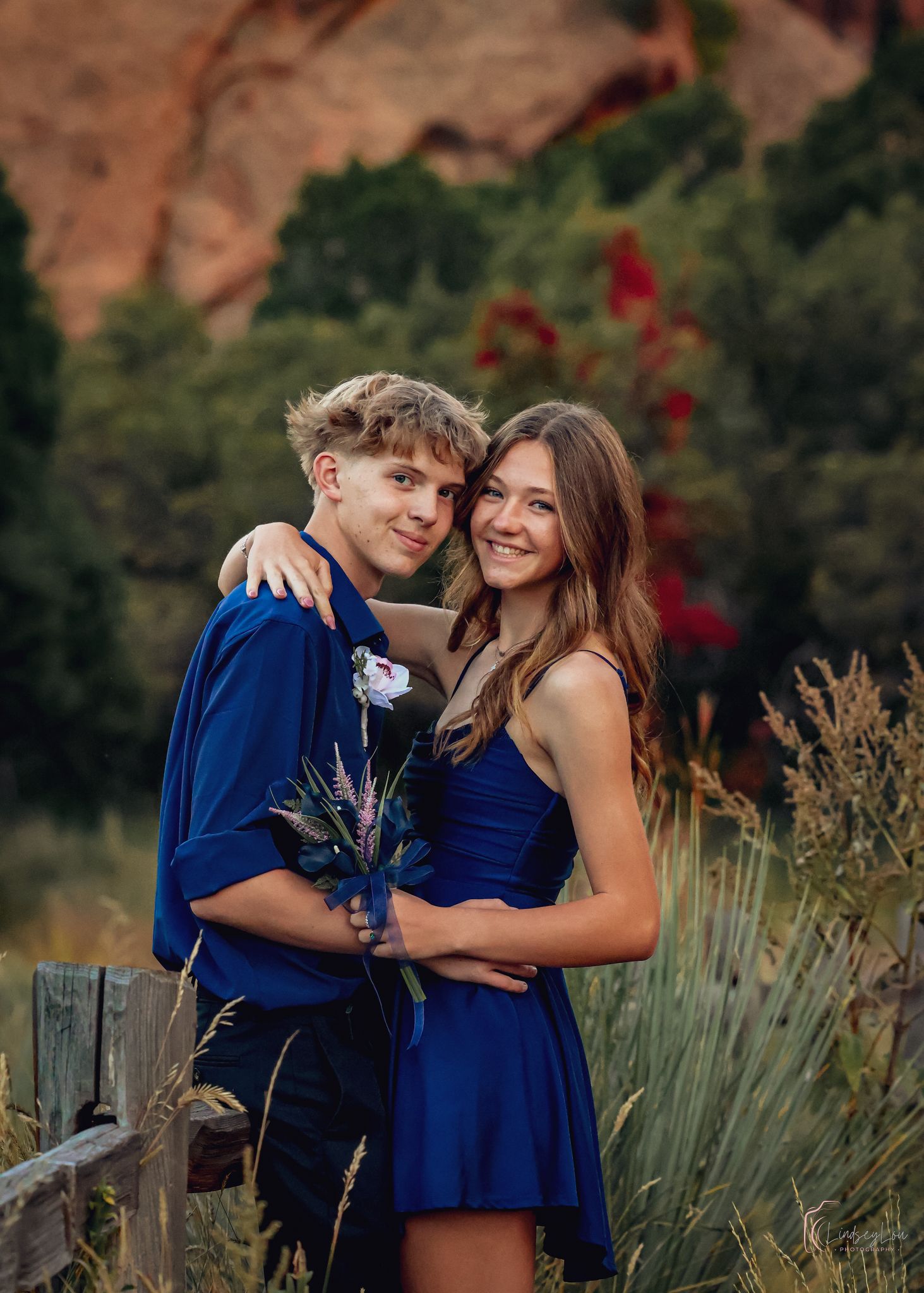 Young couple posing in front of red rocks in dress attire