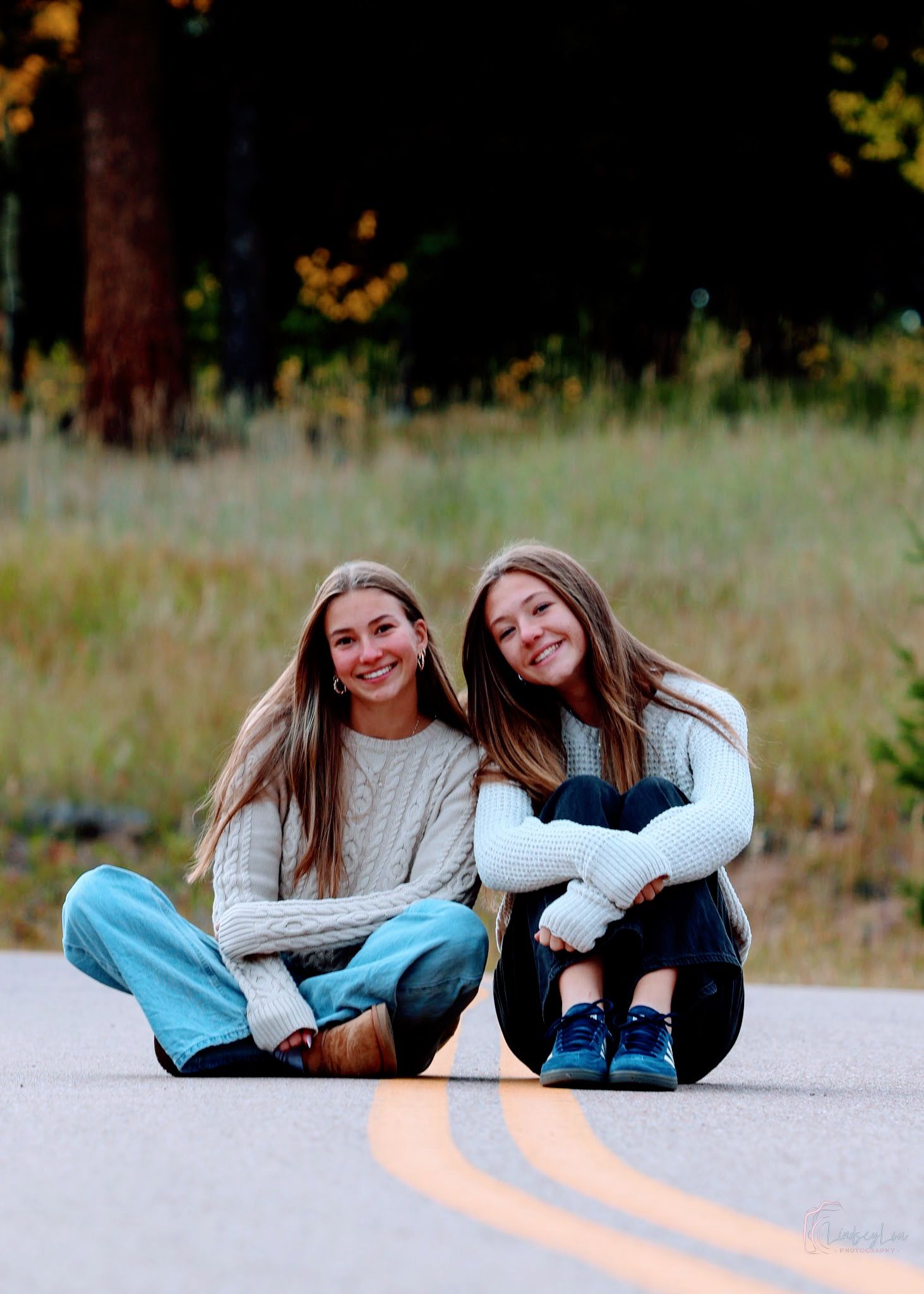 Two friend sitting in the road smiling at the camera