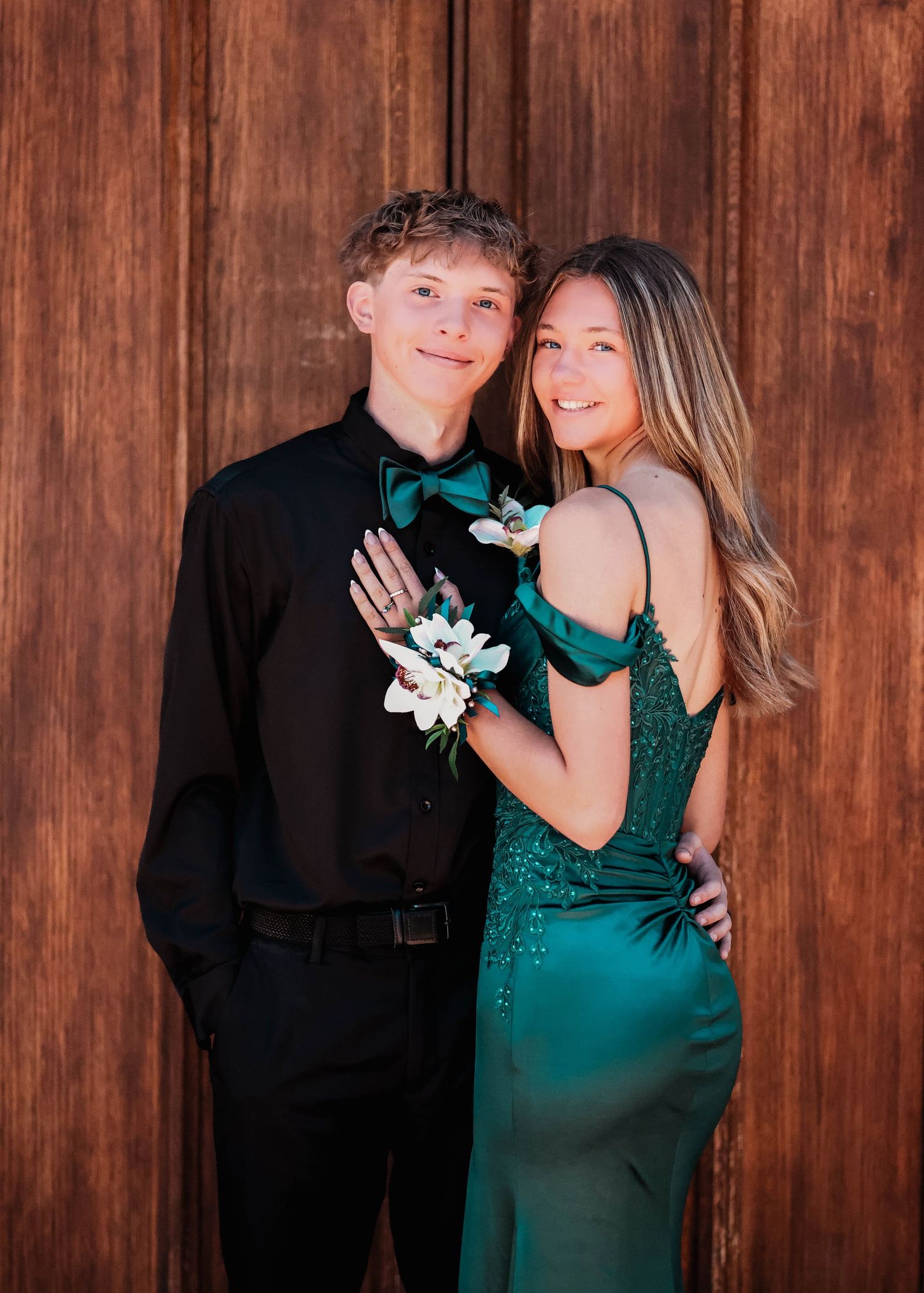 Couple posing for a picture in front of a wooden door
