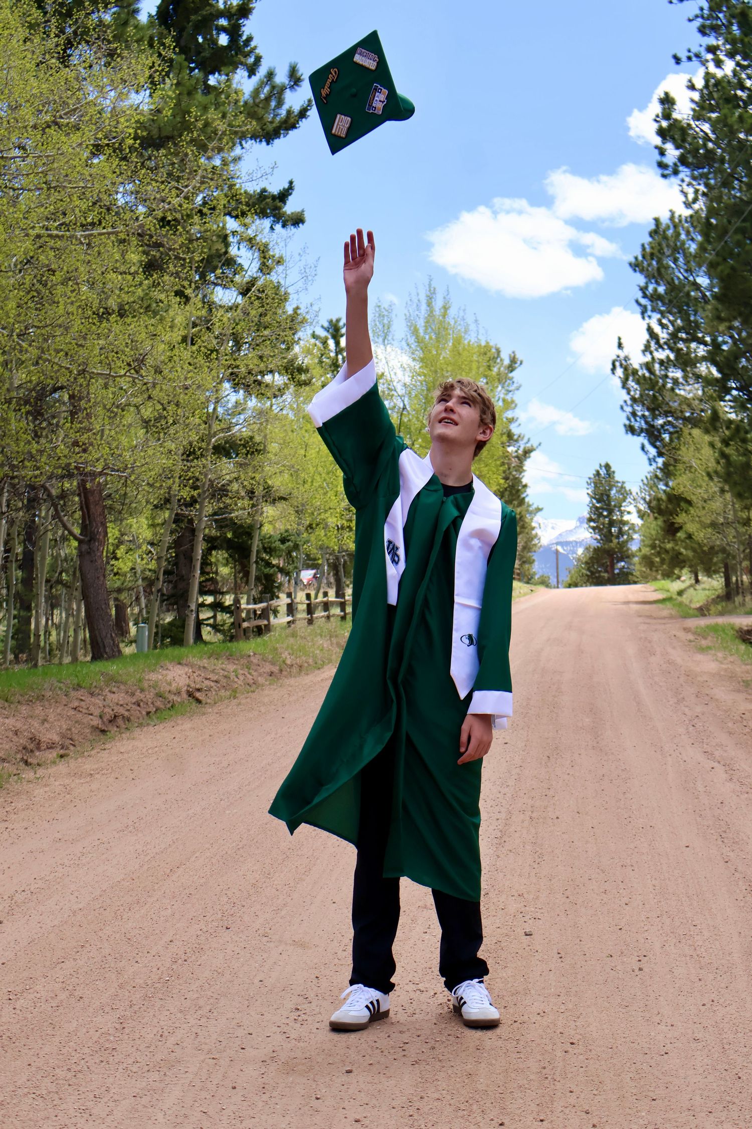 Young man in cap and gown, throwing his cap up in the air