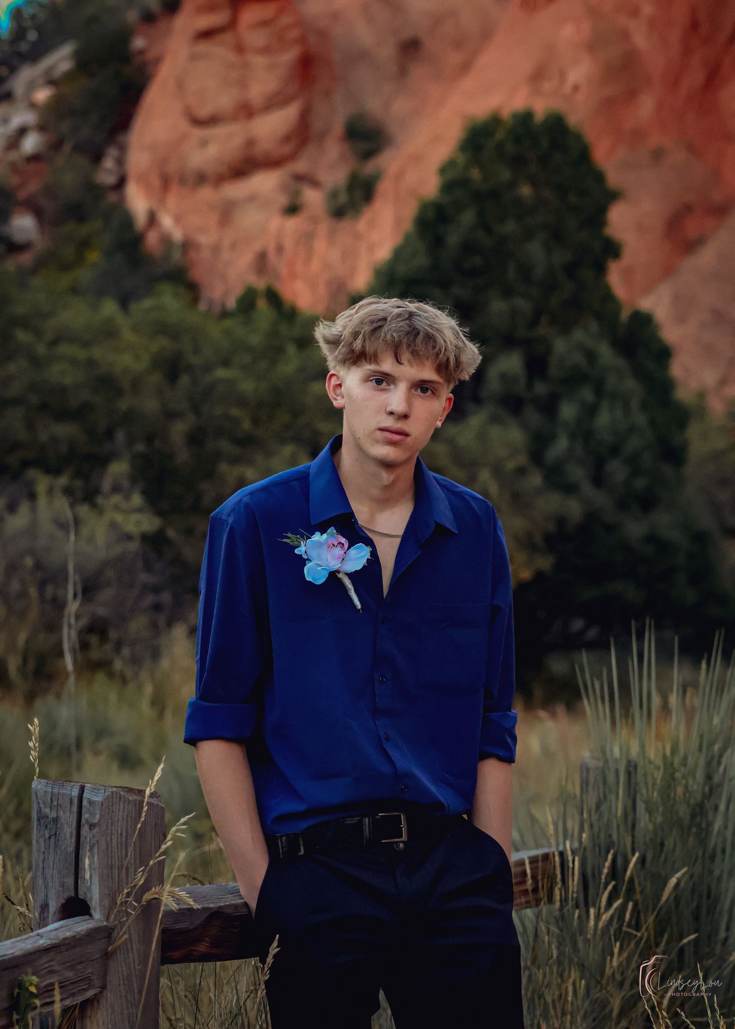 Young man posing in front of red rocks in dress attire