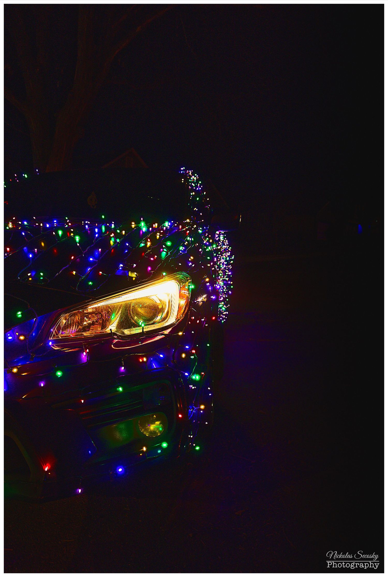 The headlight of a car wrapped in Christmas lights