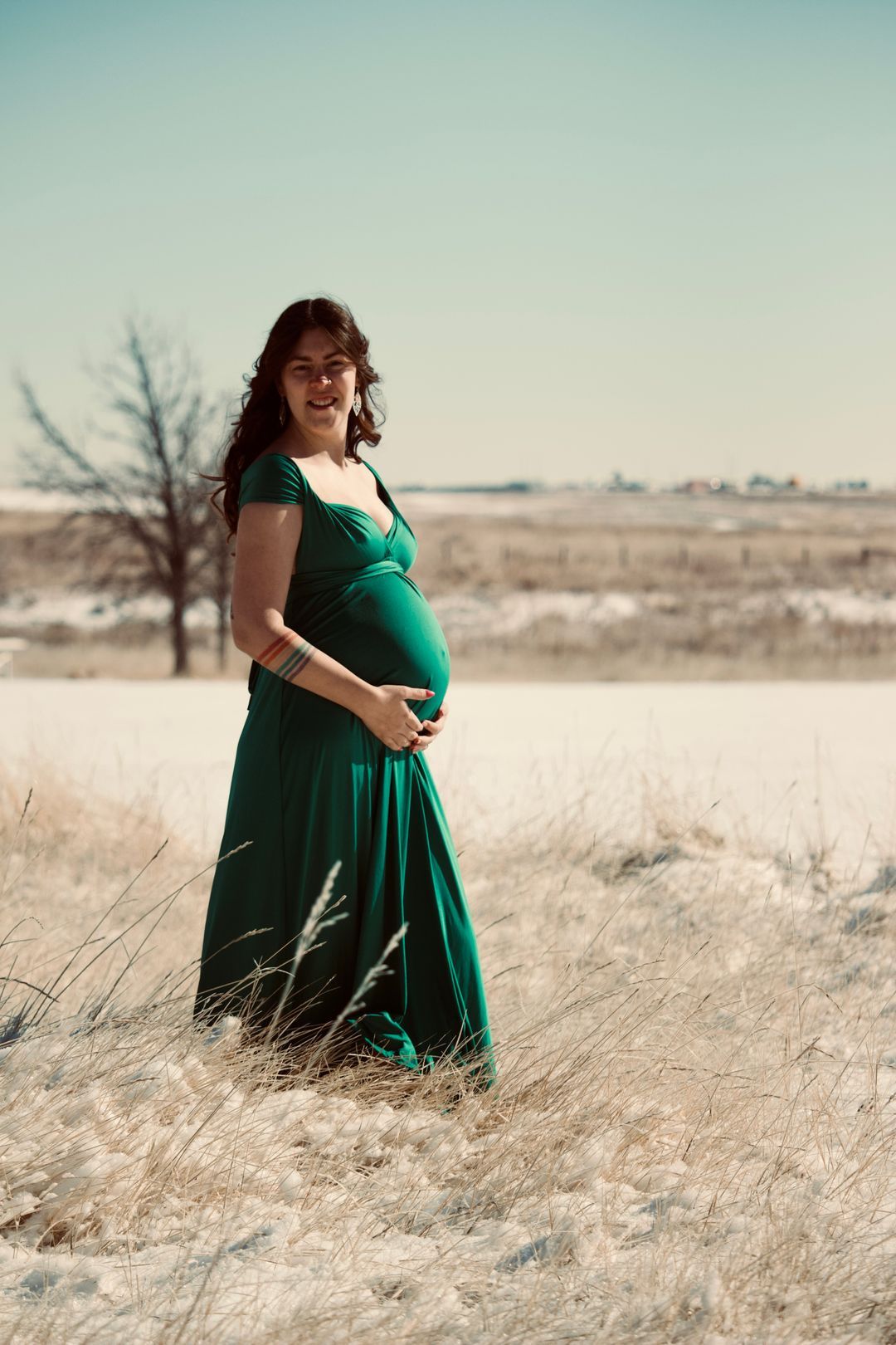 Pregnant woman posing in a field with snow