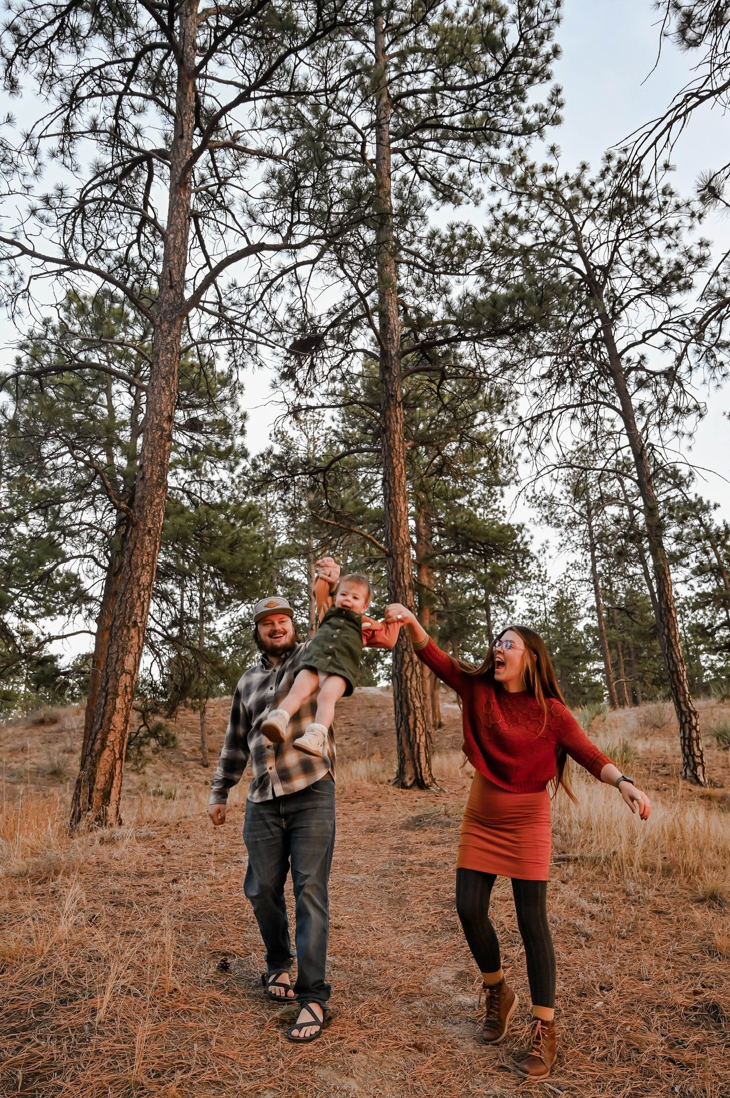 A mom and dad swinging their daughter in the air
