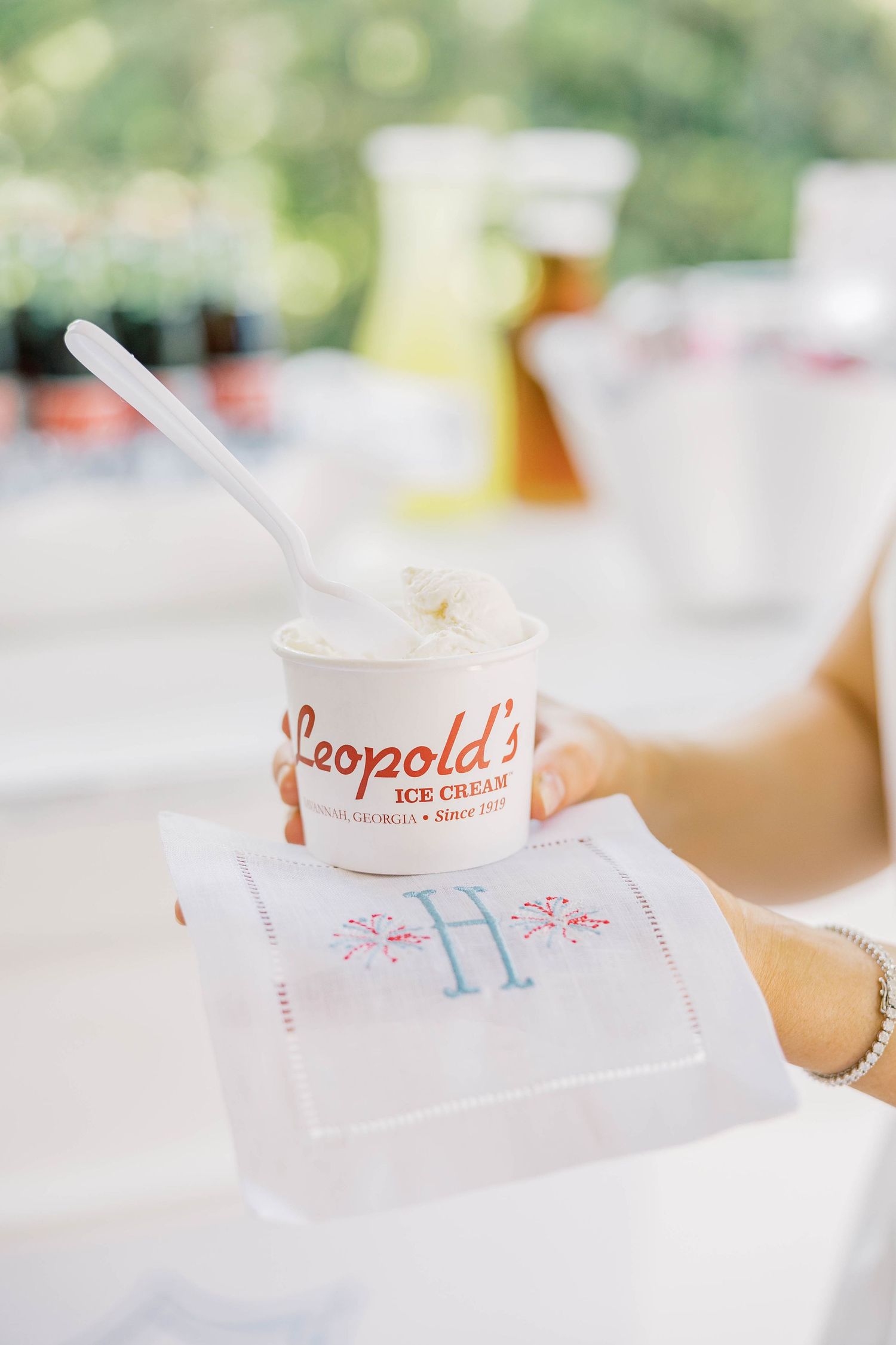 Hand holding Leopold's Ice Cream cup on monogrammed napkin at elegant outdoor event in Savannah, Georgia.