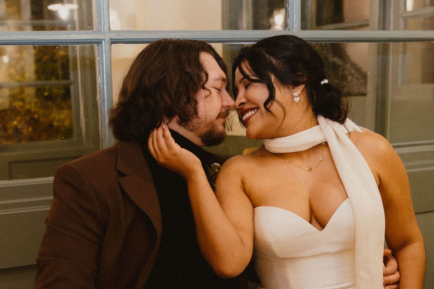 Smiling bride and groom sharing an intimate moment, bride in white halter gown.