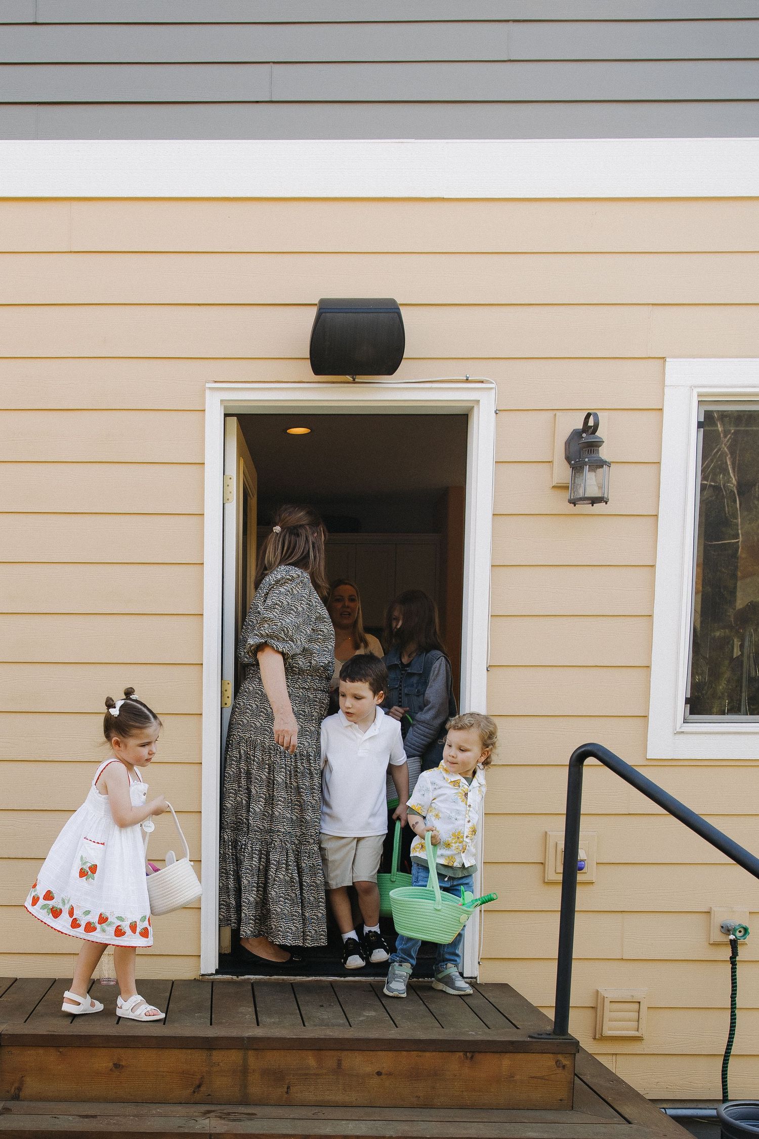 Children with Easter baskets entering home through door during holiday celebration.