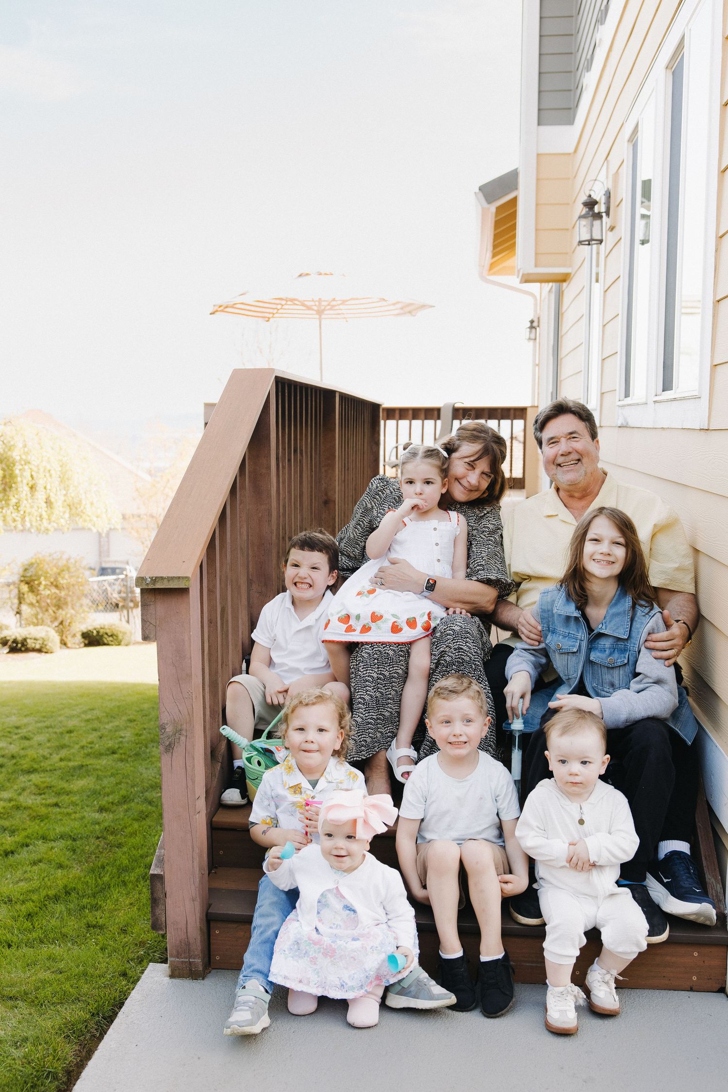 Large multigenerational family portrait on home steps with grandparents and seven children.