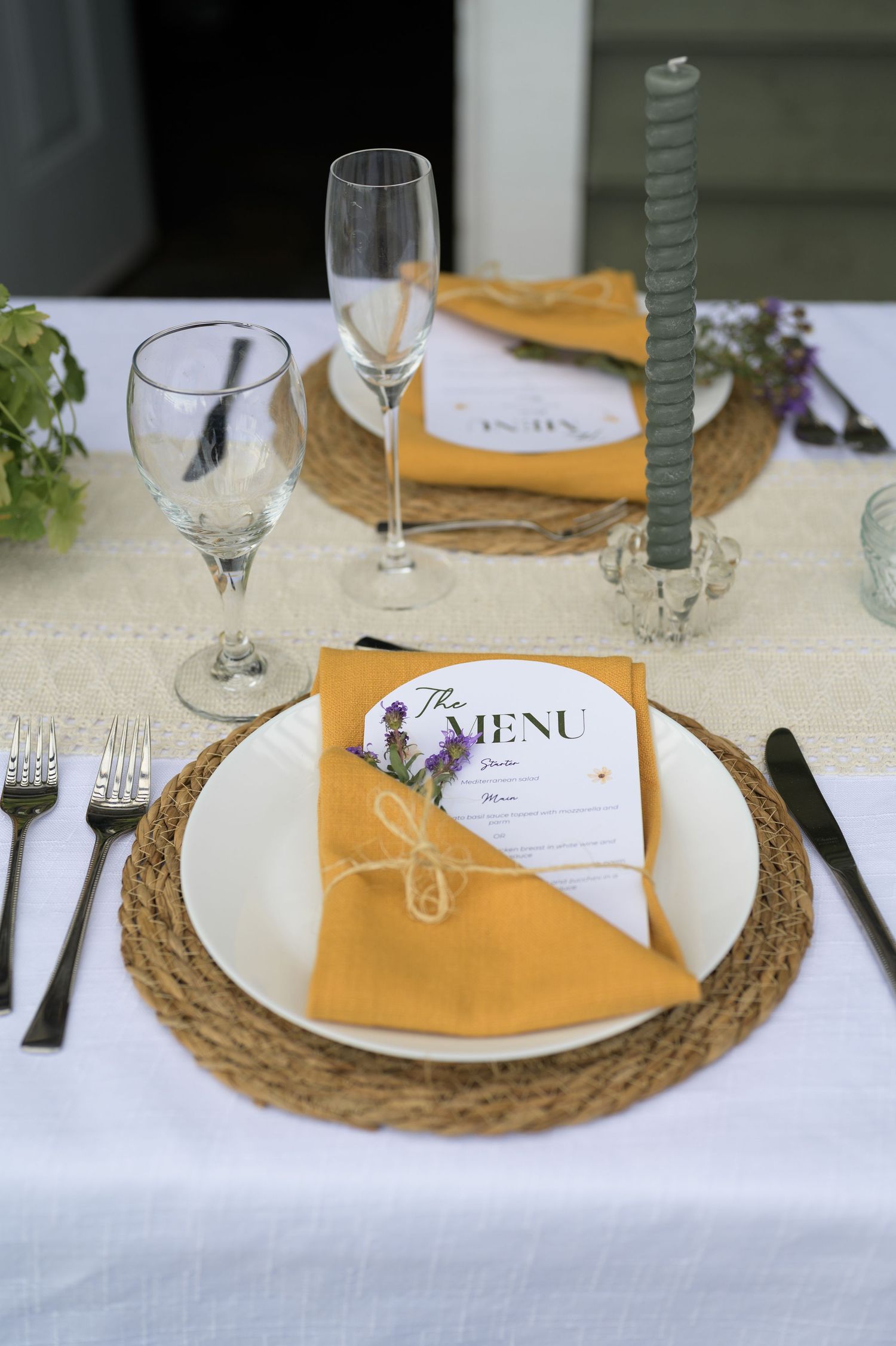 Elegant table settings with woven chargers, white linens, menu cards, and wine glasses for a formal dinner.