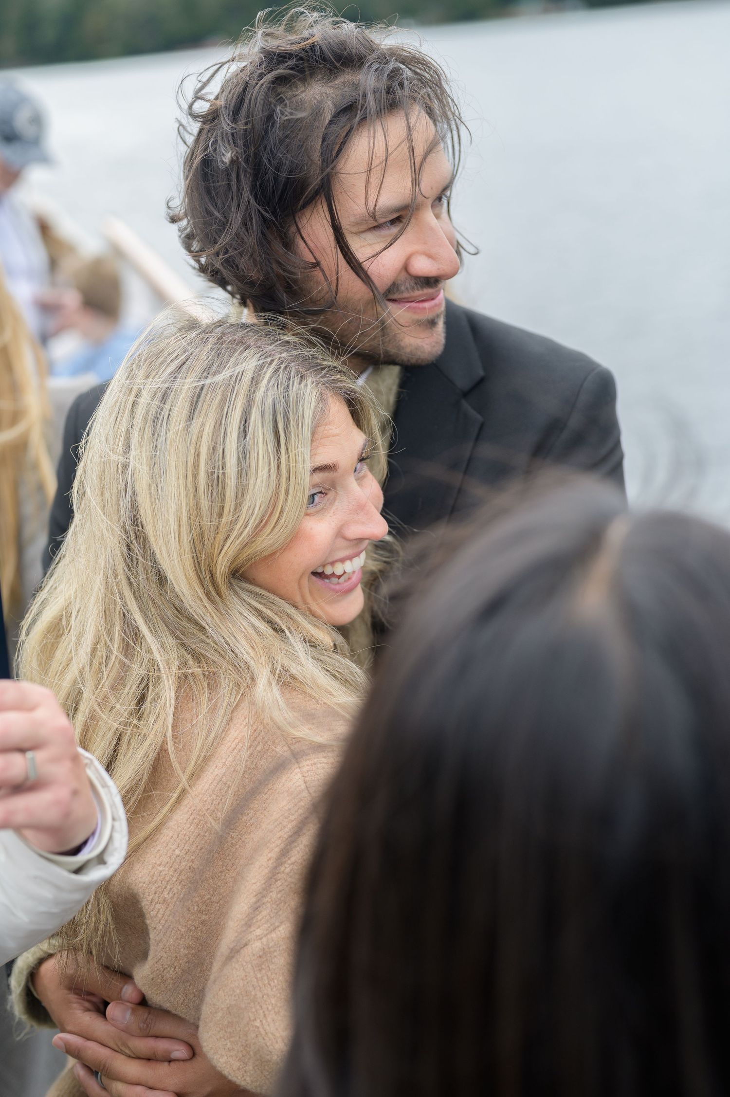 A couple shares a joyful moment together while embracing and laughing outdoors.