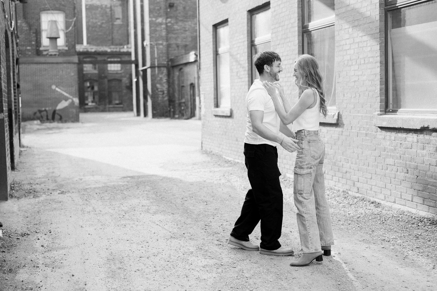 Two people in vintage clothing walk down an alley in black and white photography.