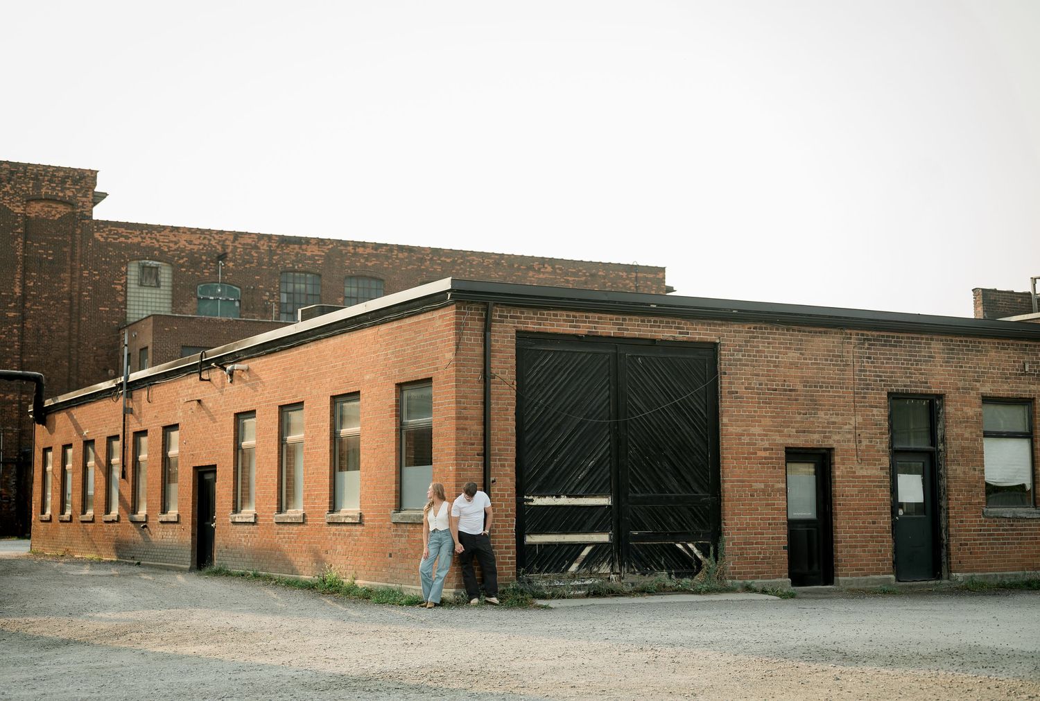 A panoramic view of an industrial brick building exterior with multiple windows and doors.