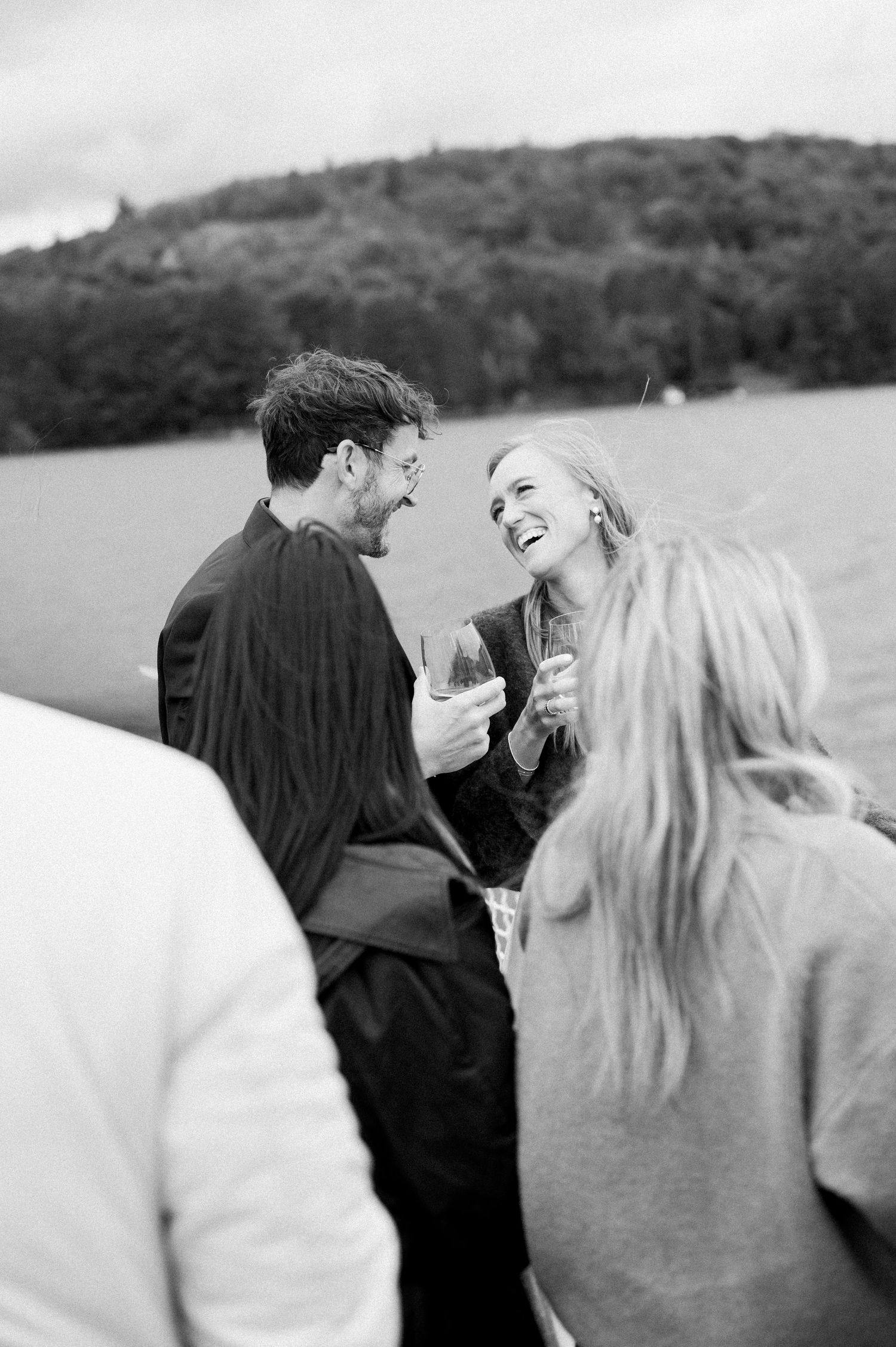 A couple shares a joyful candid moment together outdoors in black and white photography.
