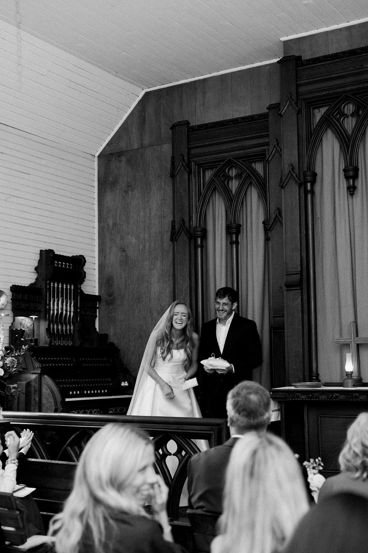 Black and white photo of wedding ceremony with guests seated in church pews during traditional service.