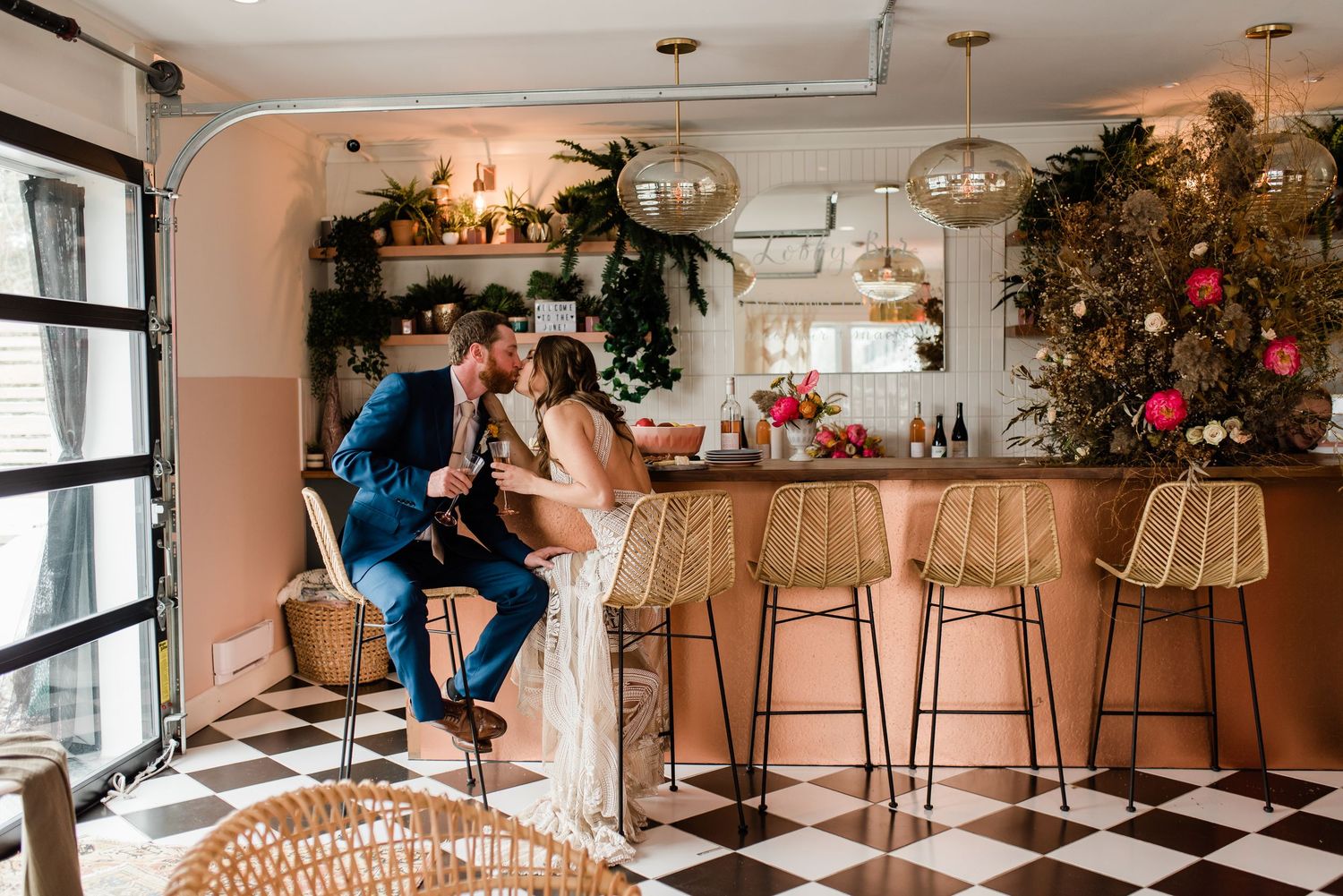 A romantic moment at a stylish bar with checkered floors, rattan seating, and hanging pendant lights.