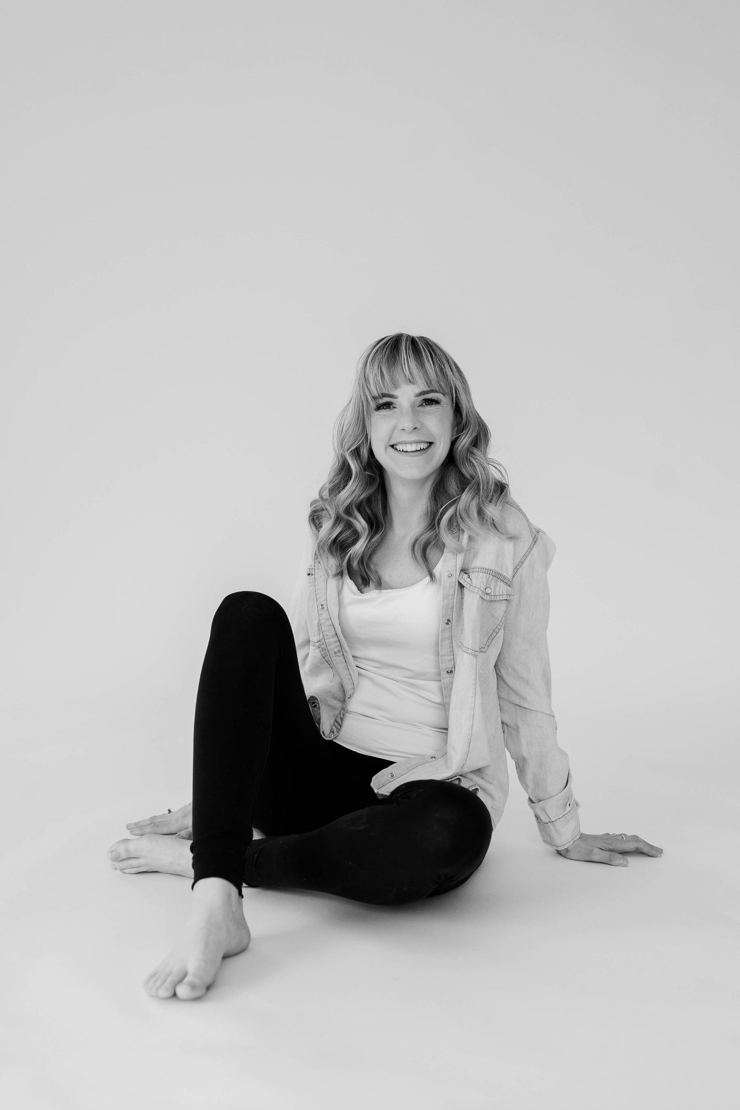A series of black and white studio portraits showing someone in casual attire lounging on a white background.