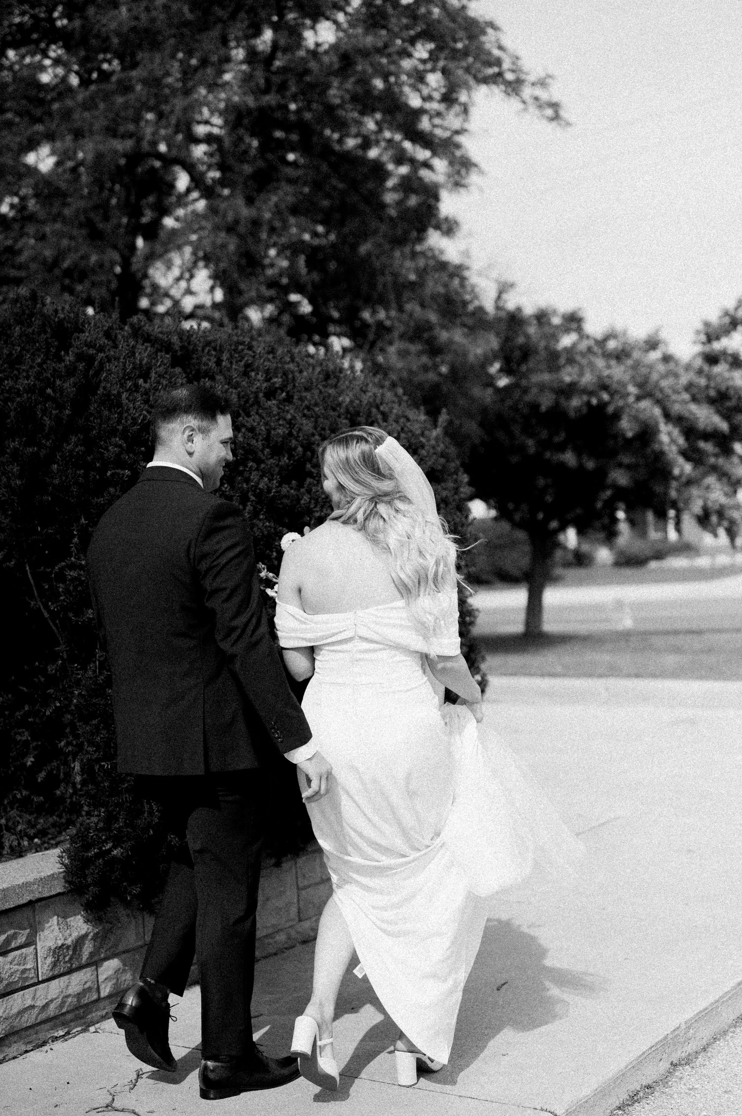 A sequence of black and white wedding photos showing a couple sitting together on a stone wall in an outdoor setting.