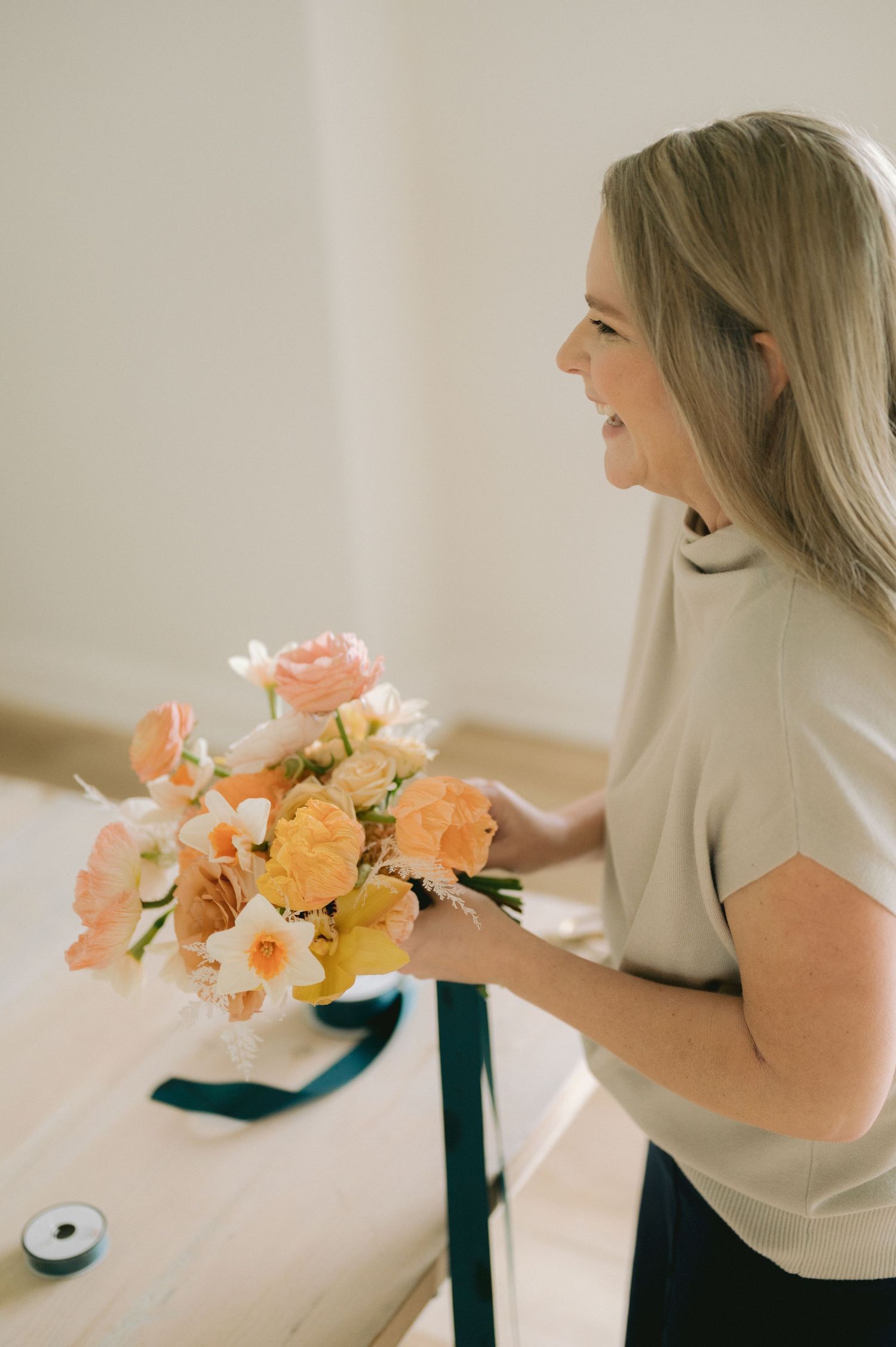 A series of images showing someone arranging delicate peach and cream colored flowers in soft natural light.