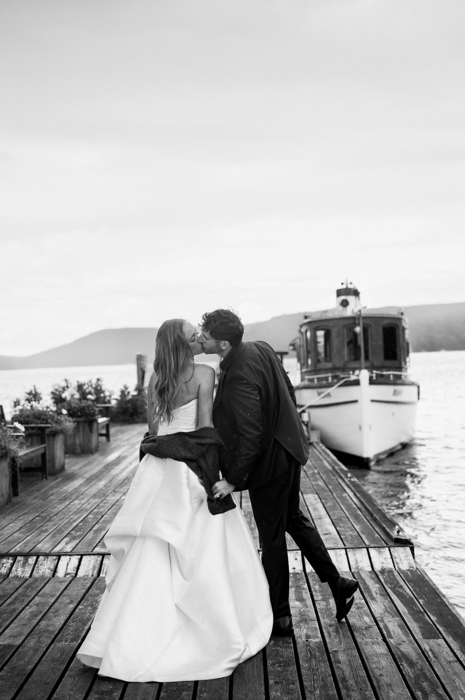 A romantic moment captured in black and white as a couple shares tender moments on a wooden dock by the water on the Lake of Bays.