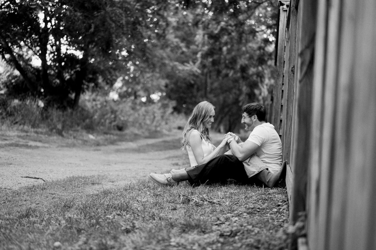 A black and white photo shows a person sitting on a bench in a tranquil outdoor garden setting.