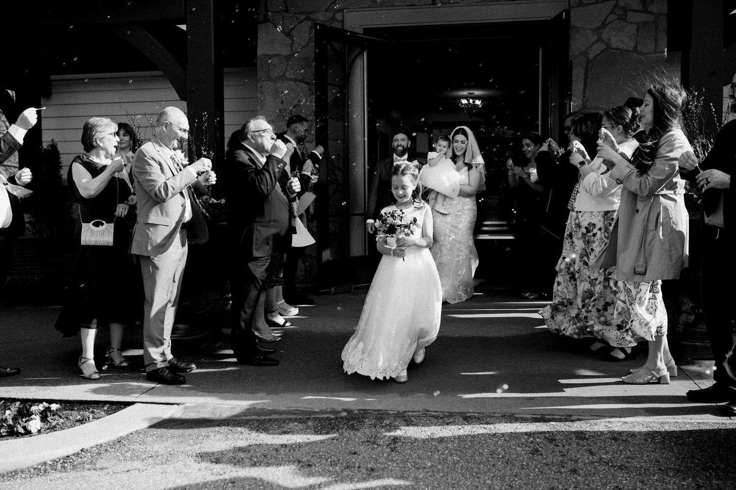 Black and white photo of a wedding celebration exit with people blowing bubbles as they exit the ceremony at Ancaster Mill.