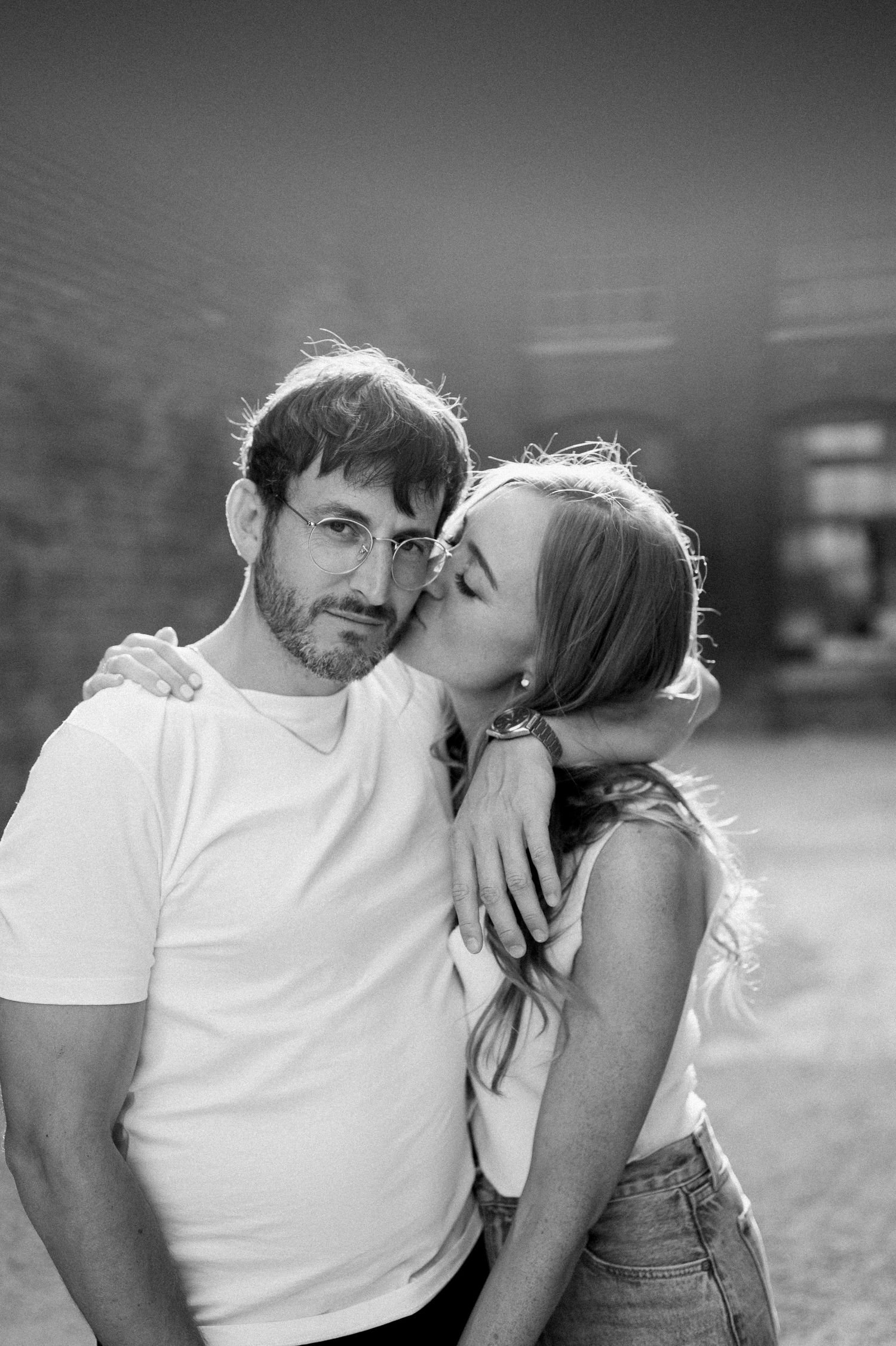A romantic black and white portrait of a couple sharing an intimate moment outdoors.