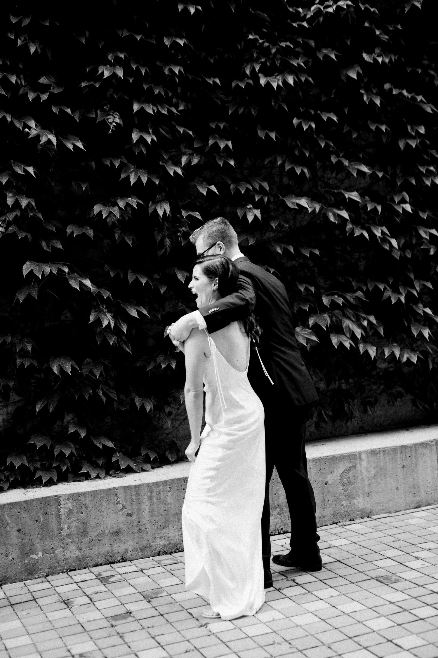 A romantic black and white sequence showing a couple in wedding attire dancing together on a stone patio.