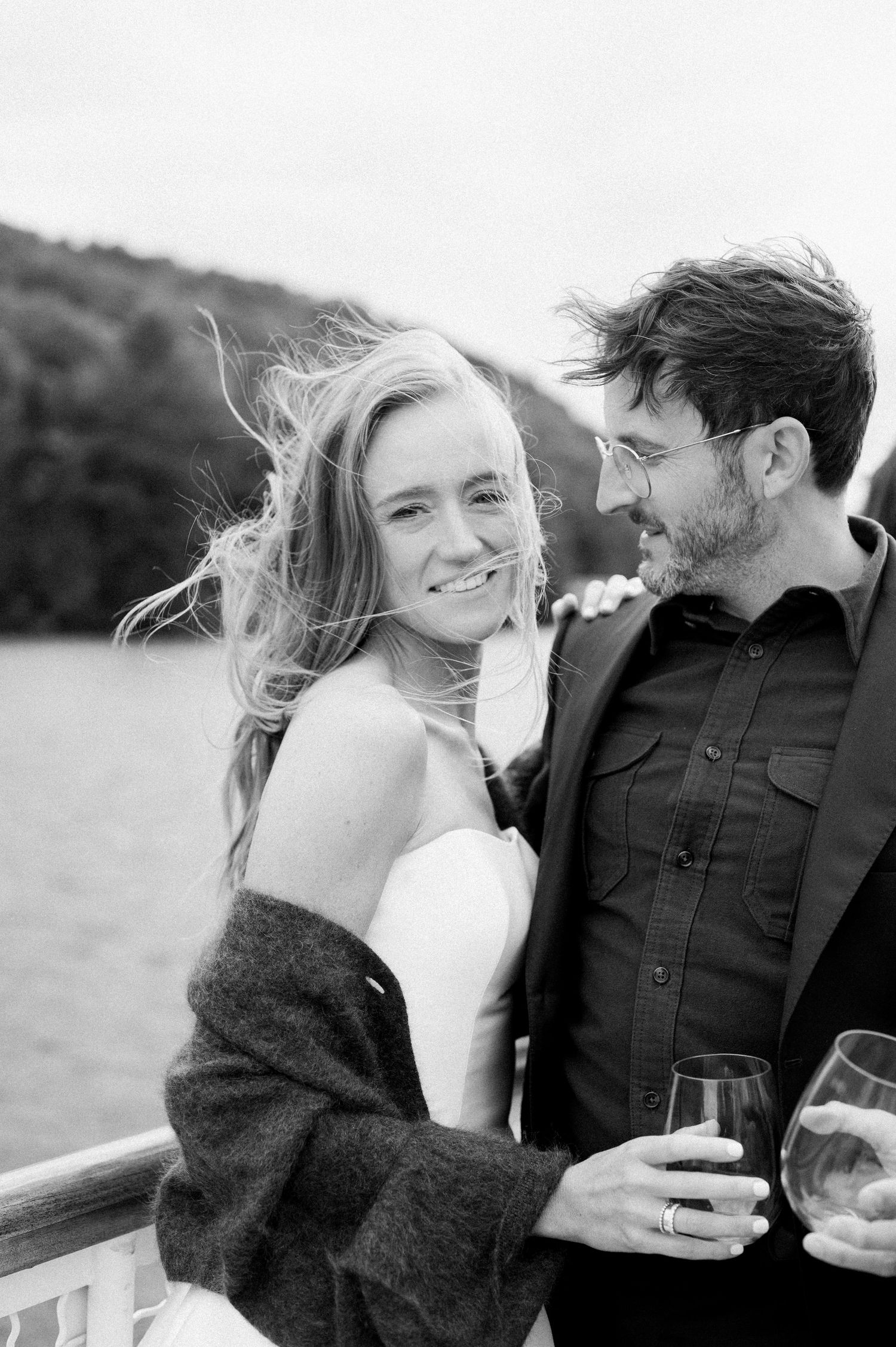 A romantic black and white photo series showing a couple sharing intimate moments while holding wine glasses outdoors.