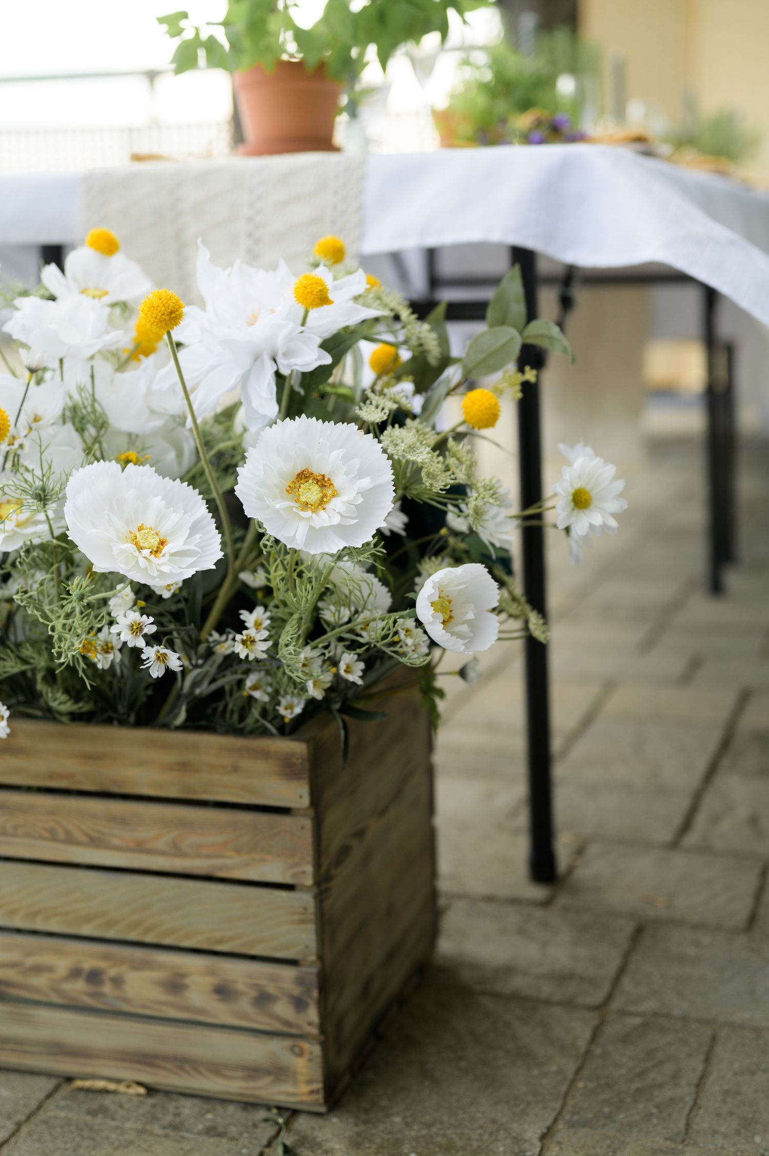 Rustic wooden crates filled with white peonies and yellow daisies arranged as wedding centerpieces.