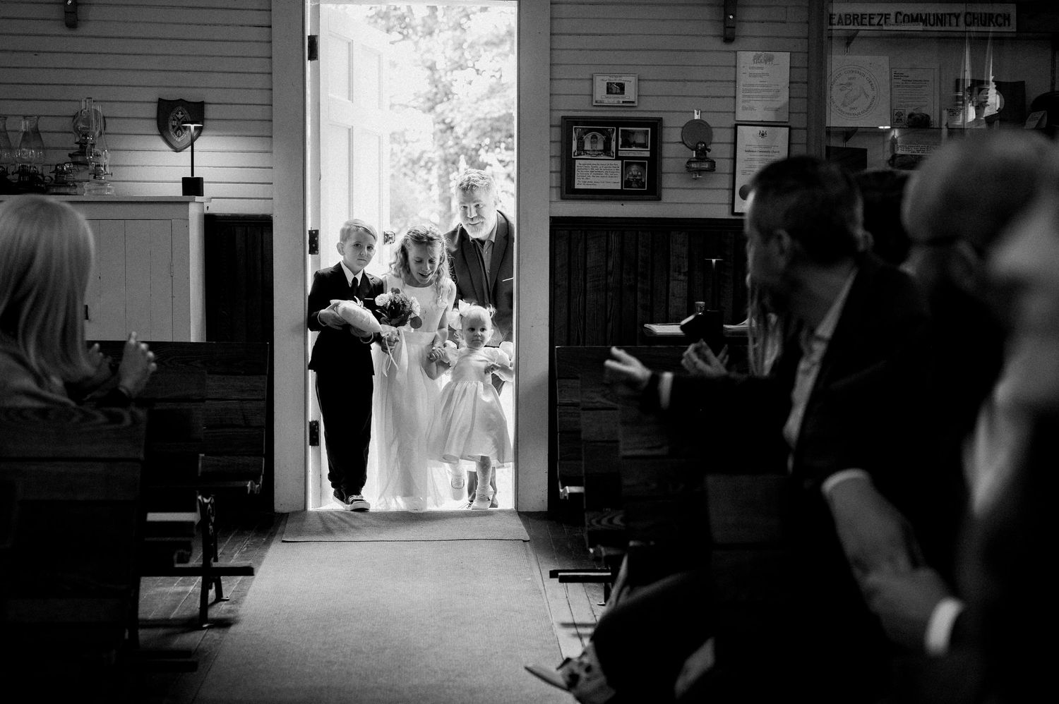 A black and white photo montage showing multiple wedding scenes and moments arranged in a horizontal strip.