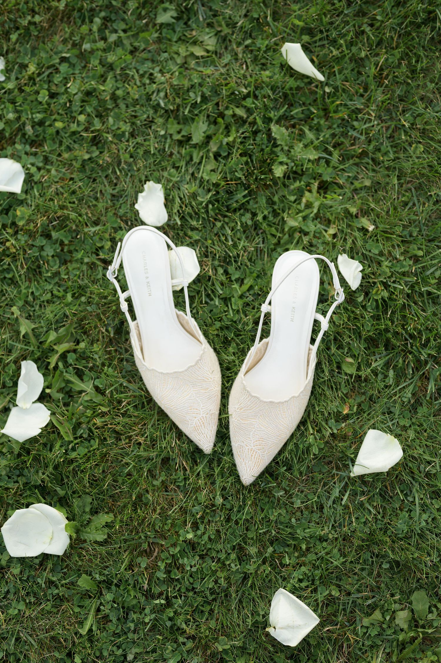White high-heeled shoes and scattered papers lay on green grass in a sequential arrangement.