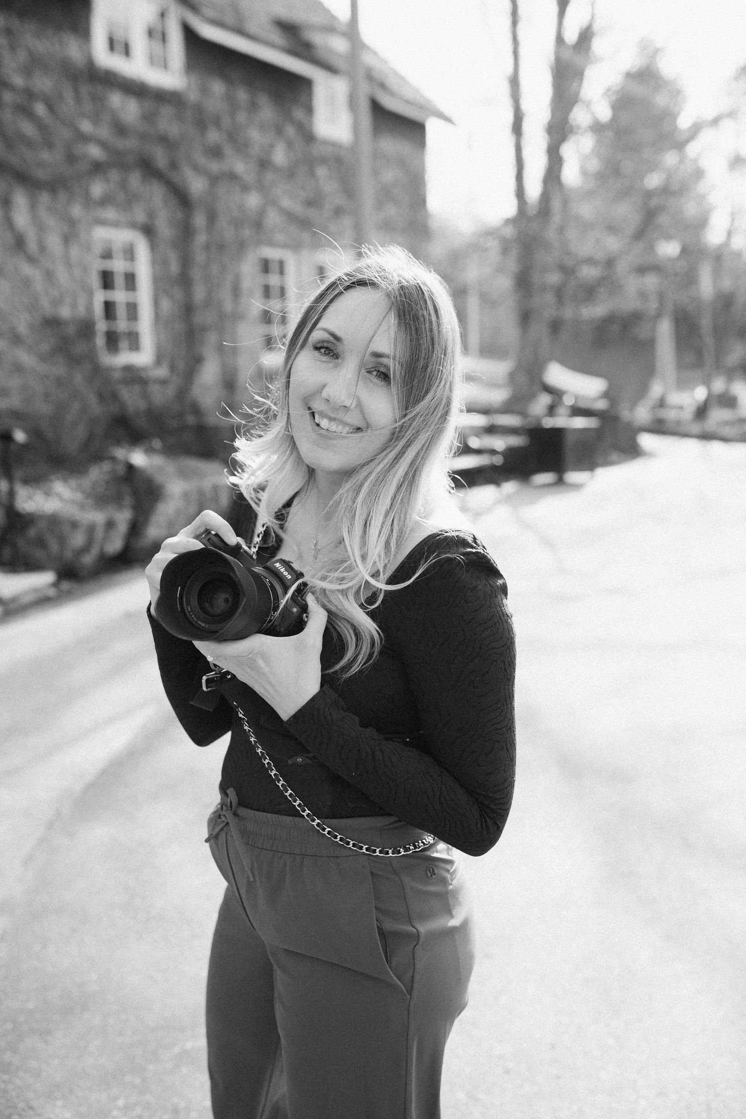 Black and white portrait series of a photographer Destiny Dawn with a nikon camera at the Ancaster Old Mill Venue.