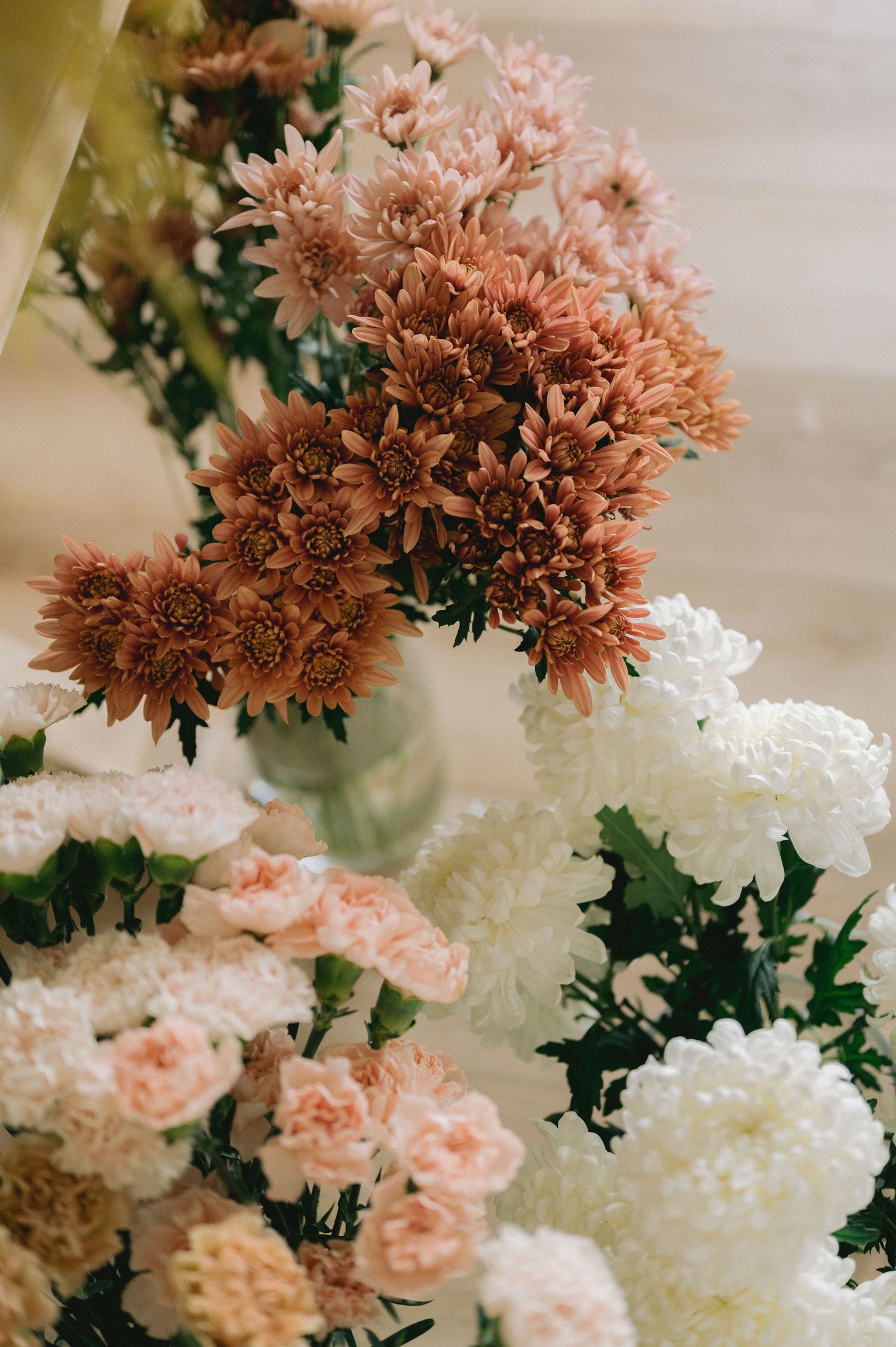Soft peach and white flowers arranged in vintage-style bouquet with chrysanthemums and roses in muted tones.